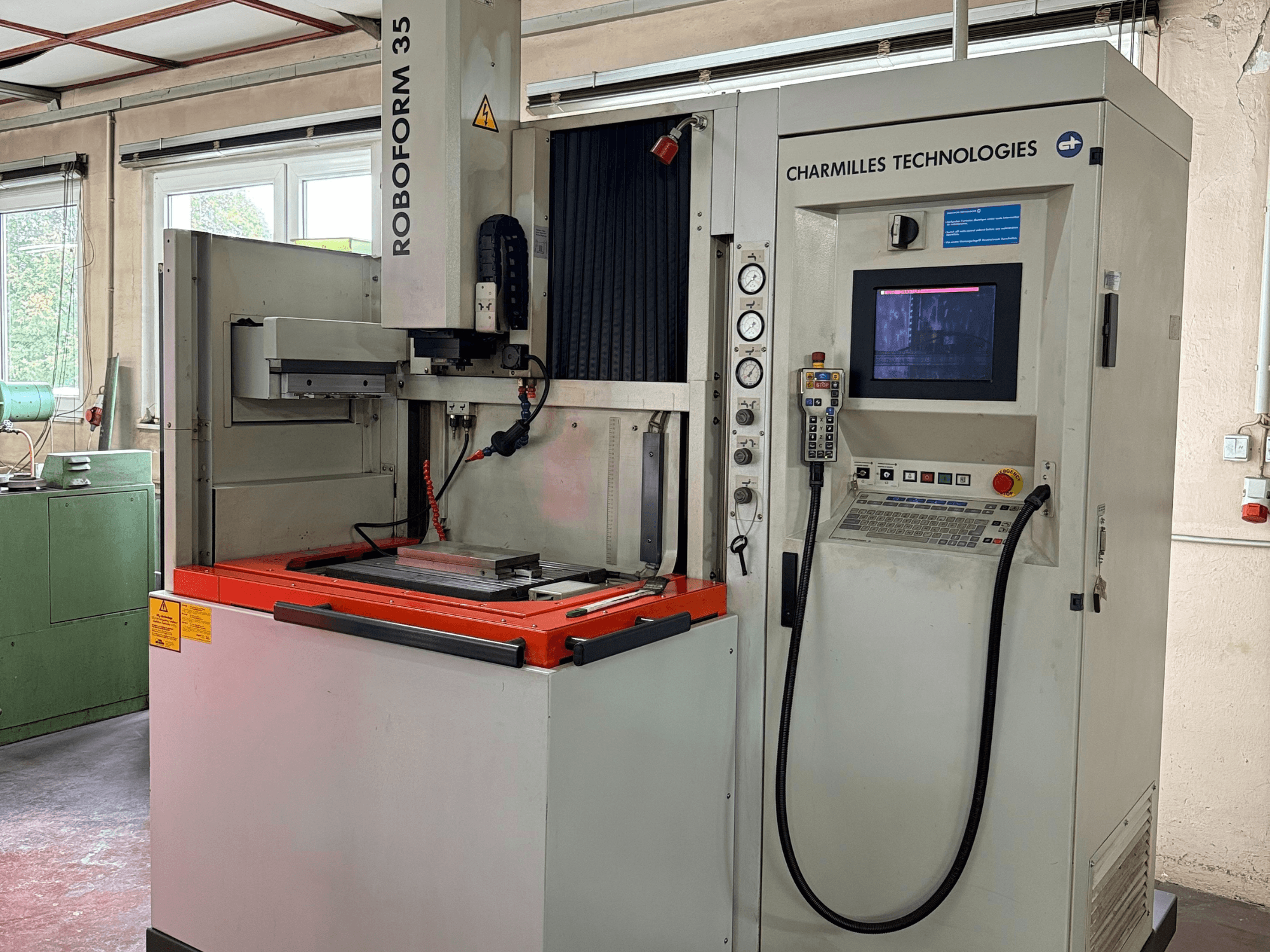 Macchina Roboforn 35 di Charmilles Technologies, vista frontale, con pannello di controllo, utensili montati ed etichette di sicurezza.