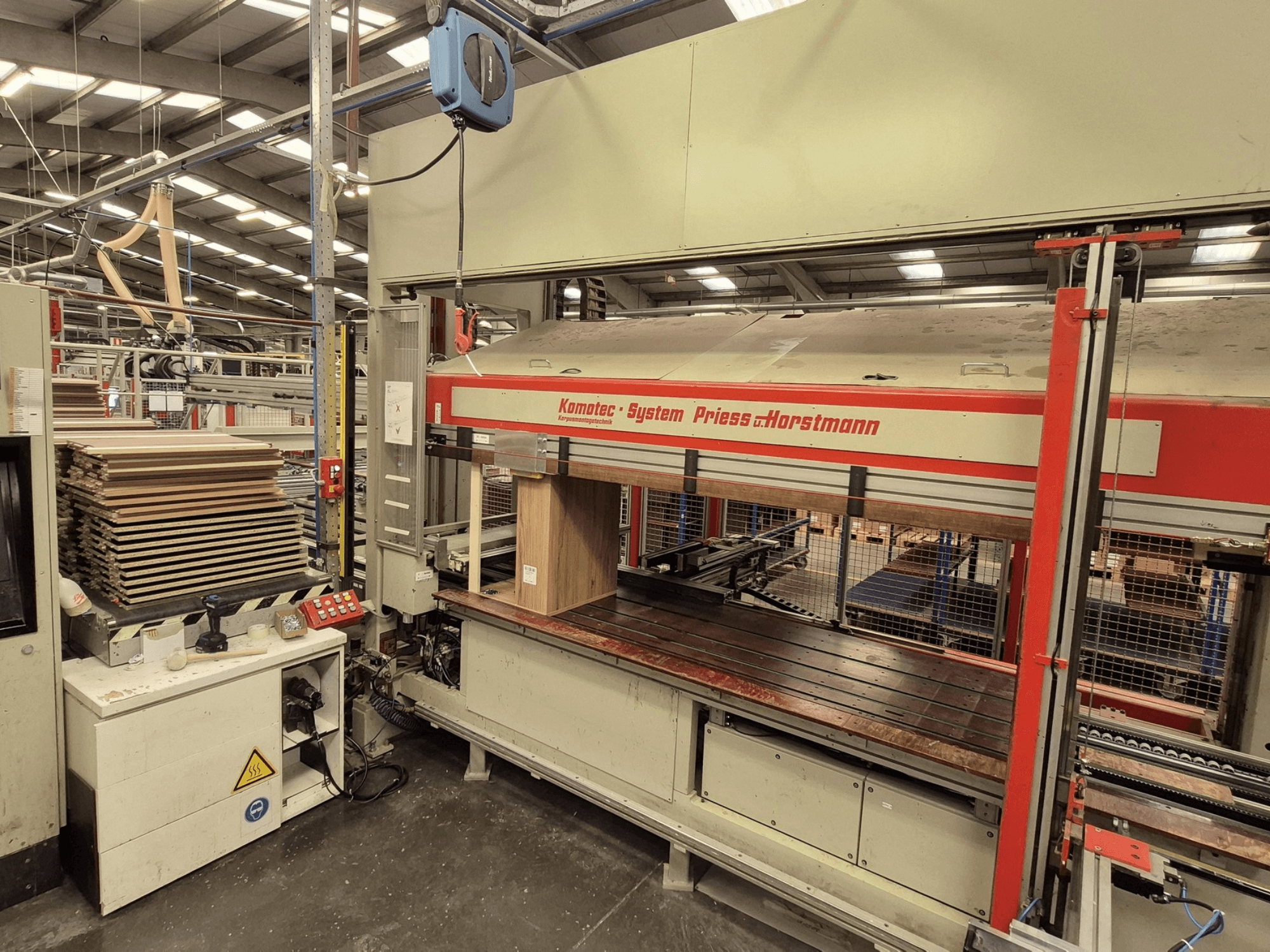 Pressa per impiallacciatura KP-5-CNC di PREISS U HORTSTMANN, vista frontale, con fogli di impiallacciatura impilati e pannello di controllo.