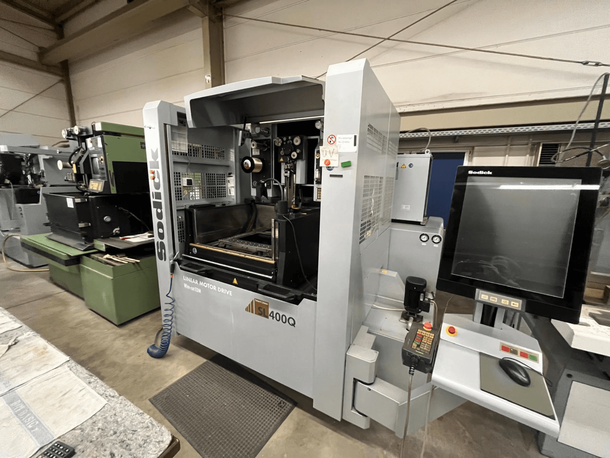 Macchina CNC a motore lineare Sodick SL400Q, vista frontale con pannello di controllo digitale e display in un'officina.
