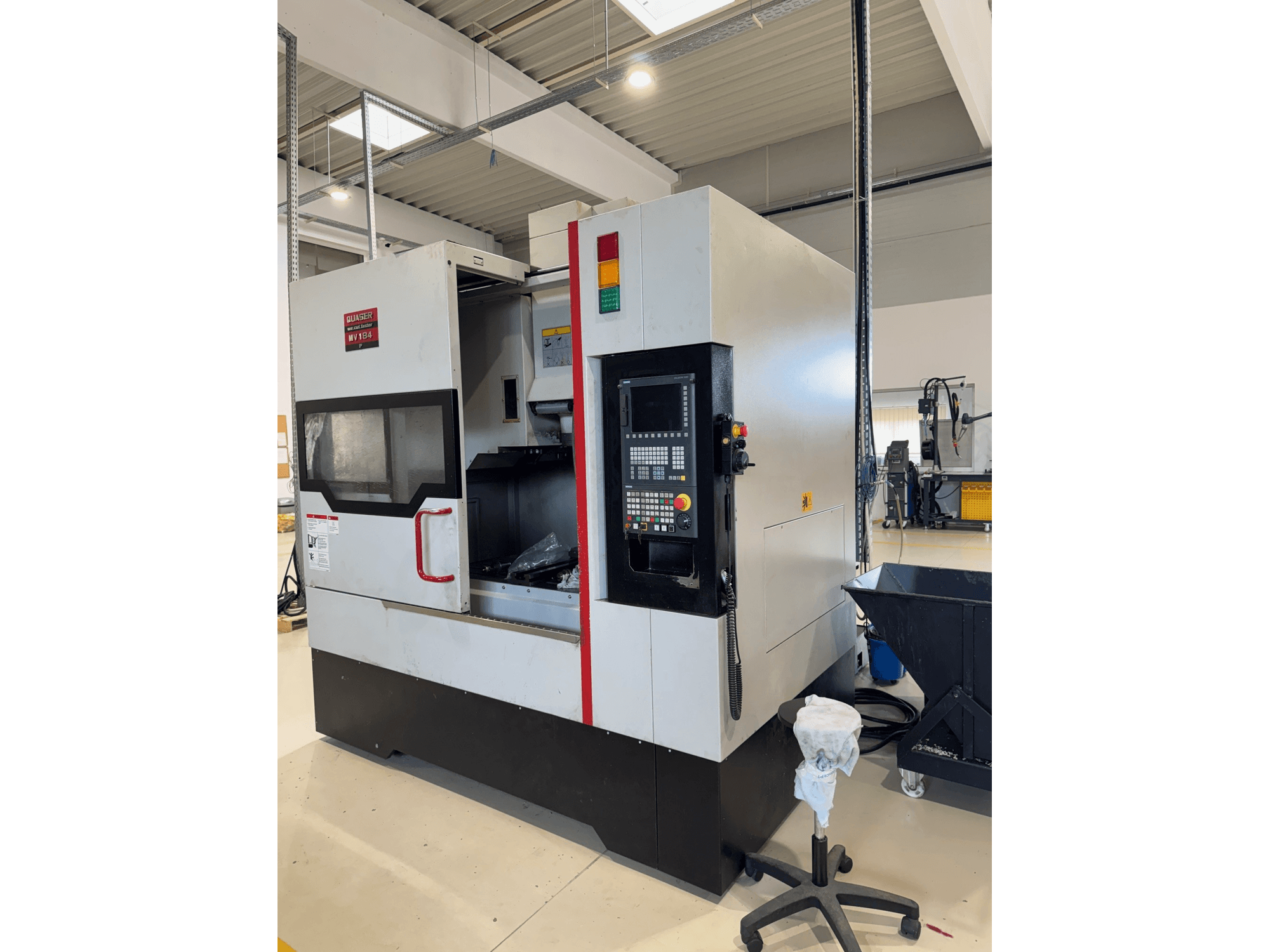 Centro di lavorazione verticale Quaser MV184P/12B, vista laterale, con in primo piano il pannello di controllo e la parte anteriore aperta che lascia intravedere l'area di lavorazione.