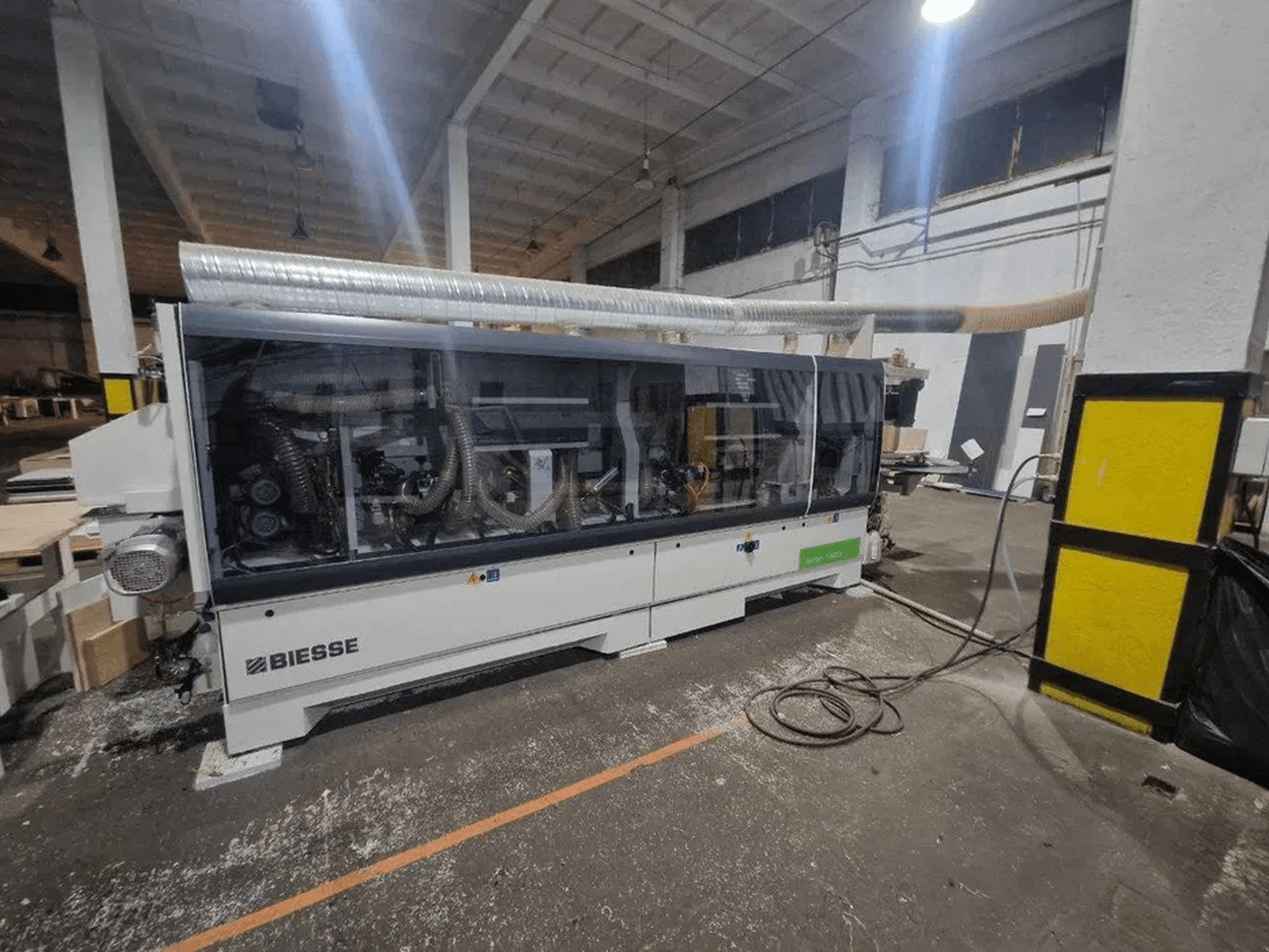 Una bordatrice BIESSE Akron 1440 A in un'officina, caratterizzata da una copertura trasparente e da componenti meccanici a vista.
