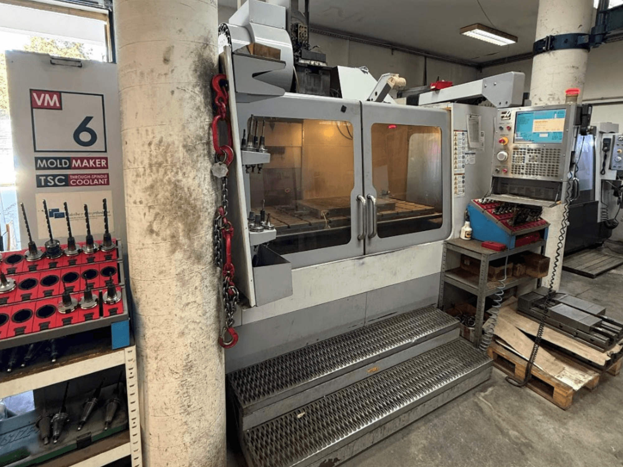 Centro di lavorazione verticale HAAS VM-6 HE visto frontalmente, con comandi, sistema di raffreddamento e magazzino utensili ben visibili.