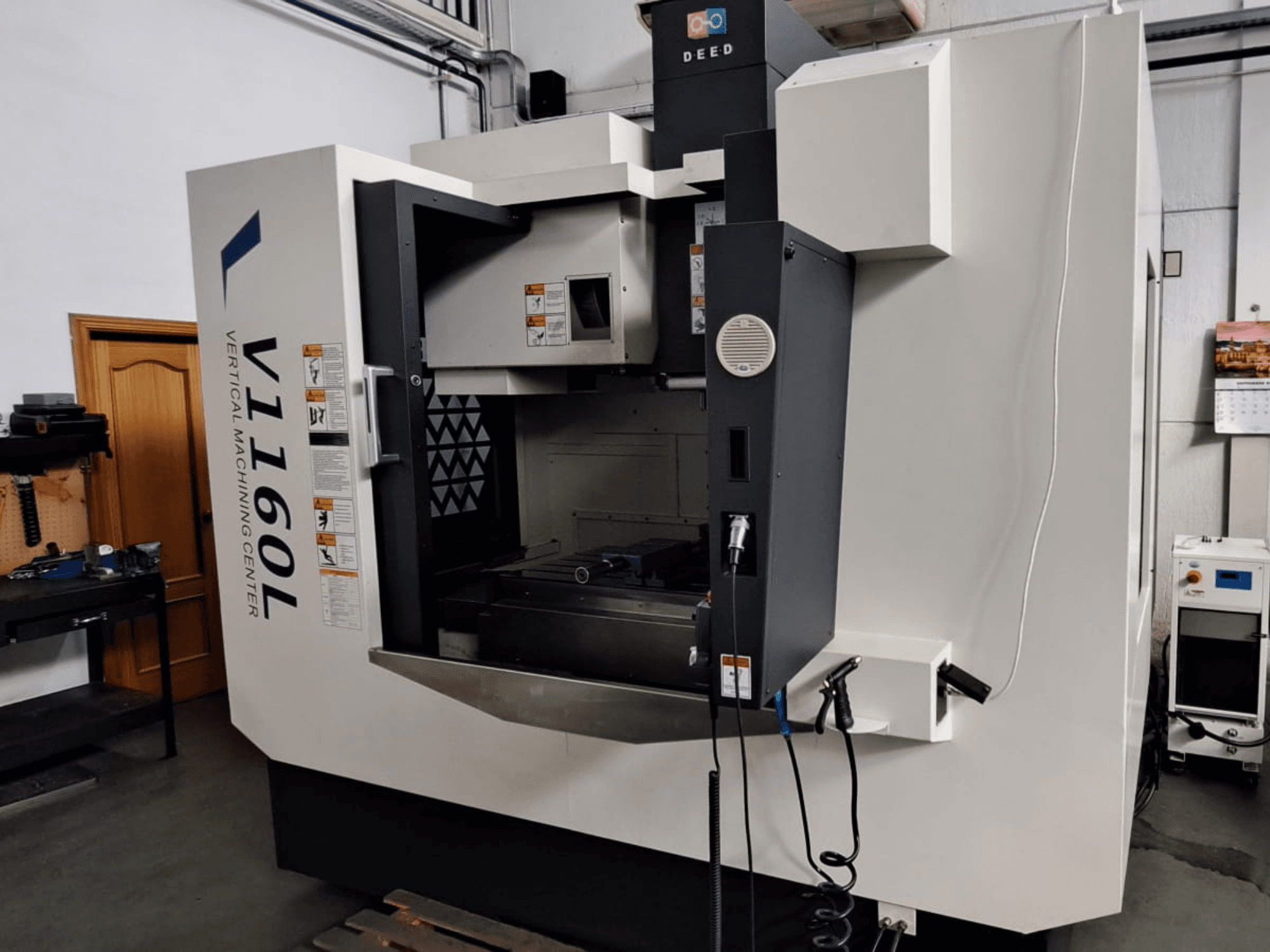 Centro di lavoro verticale DEED V1160L in vista frontale, che mostra i comandi e la configurazione interna con gli utensili vicini.