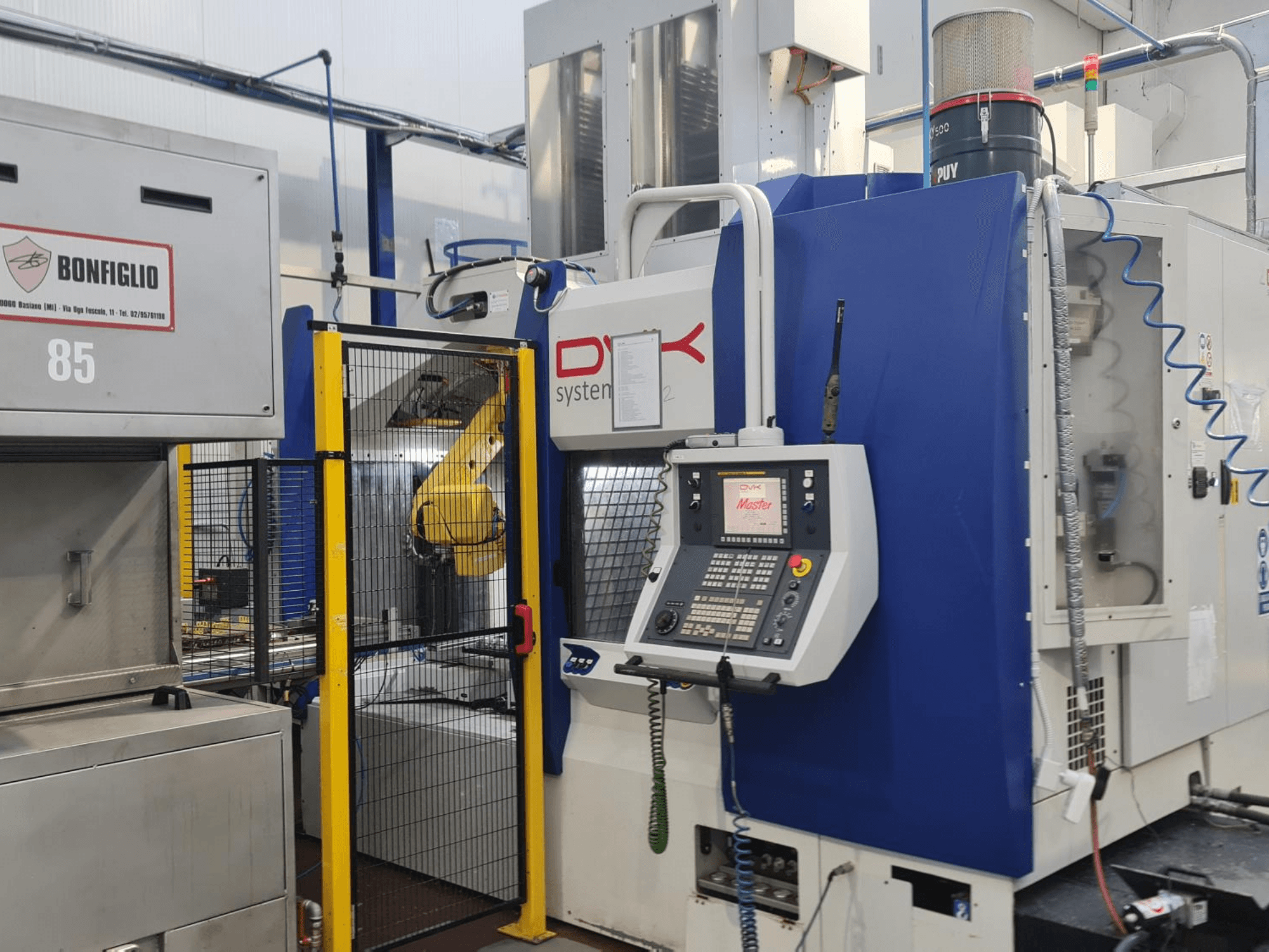 Centro di lavorazione orizzontale DVK System Master, vista frontale, con pannello di controllo, cancello di sicurezza e braccio robotico.