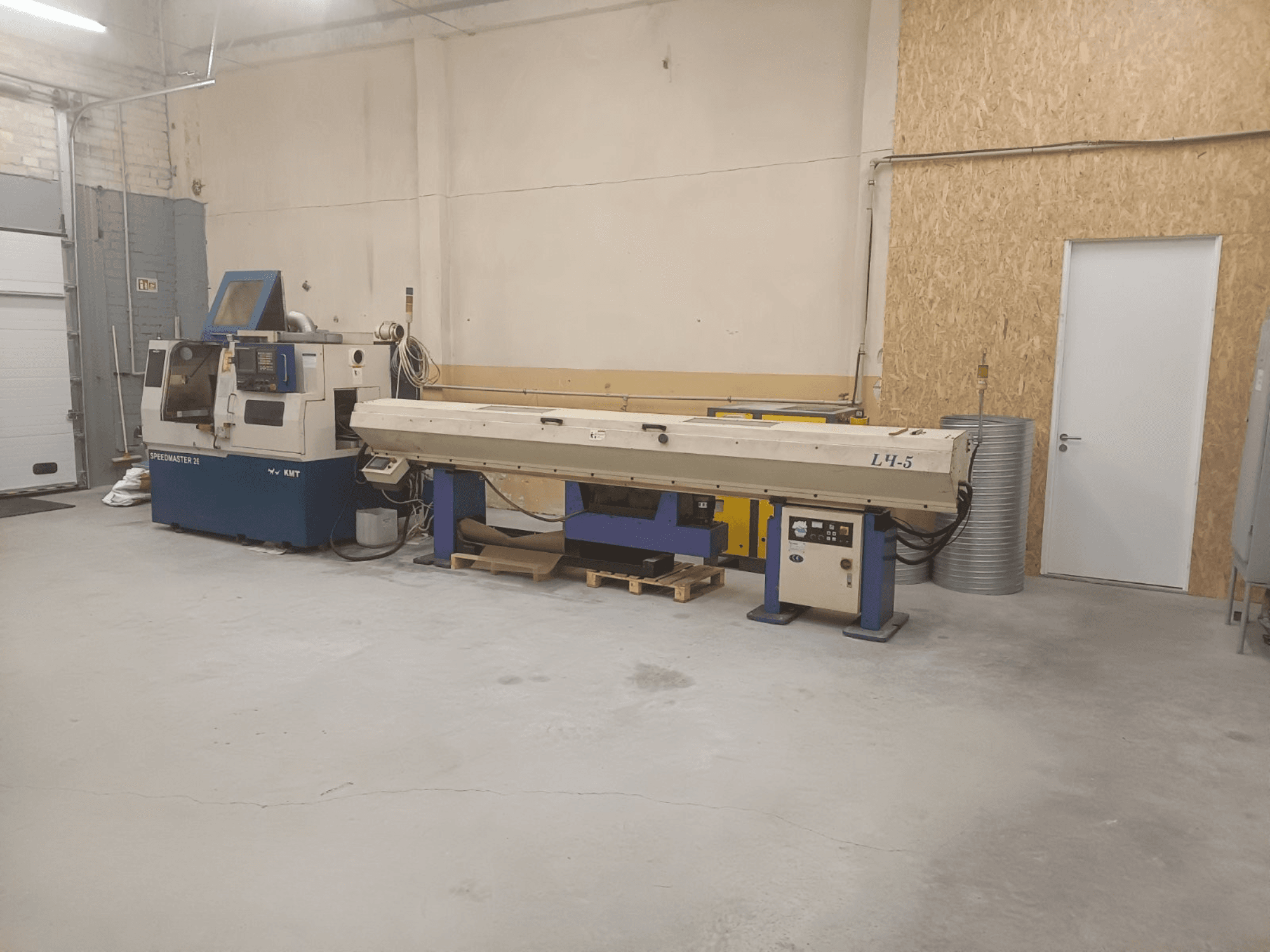 Officina industriale con macchina KMT Speedmaster 34 e L4.5, vista dal davanti, con comandi e macchinari visibili.