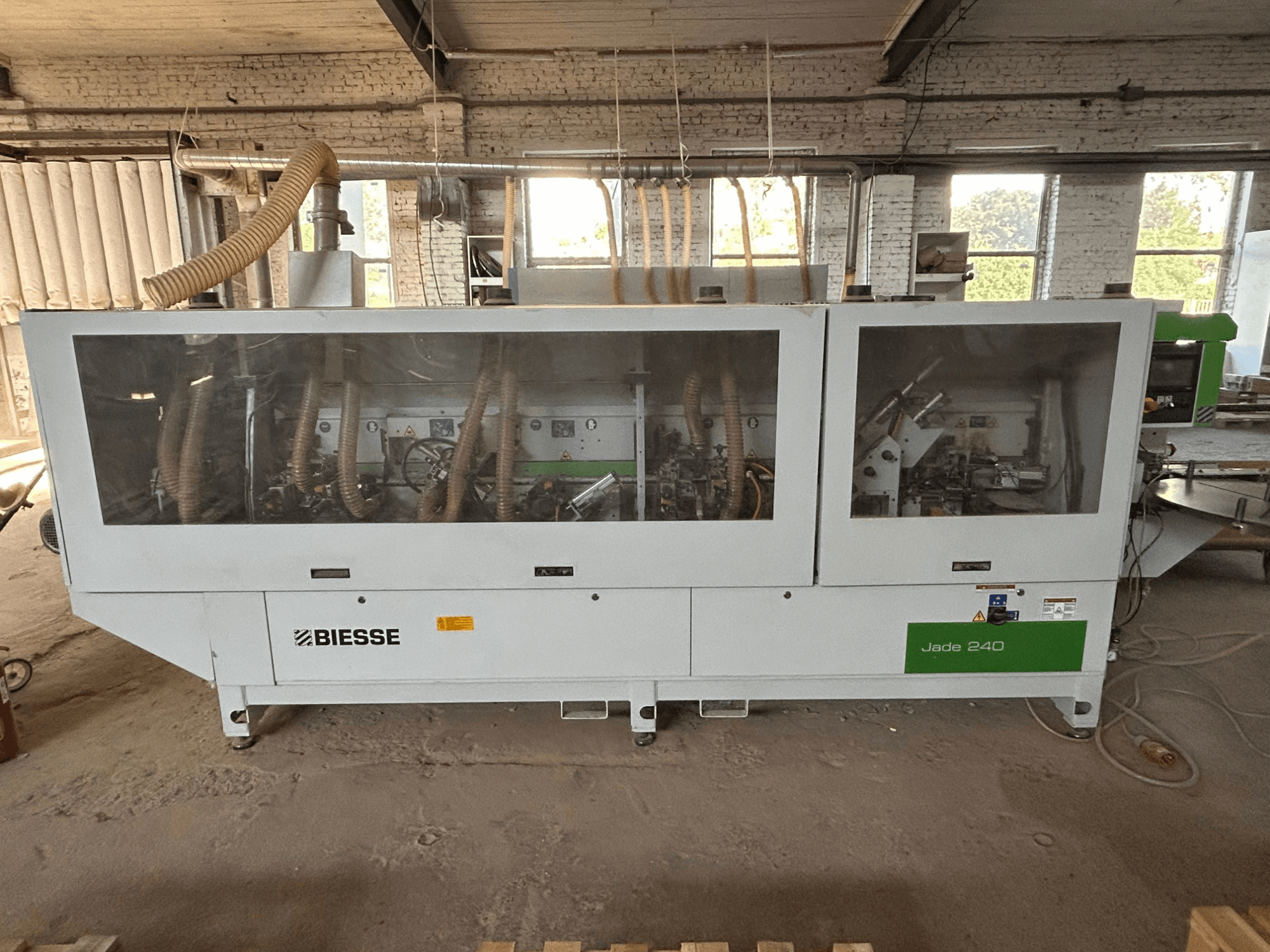 Bordatrice BIESSE Jade 240 nei colori bianco e verde, vista frontale che mostra il pannello di controllo e i dettagli dell'interno della macchina.