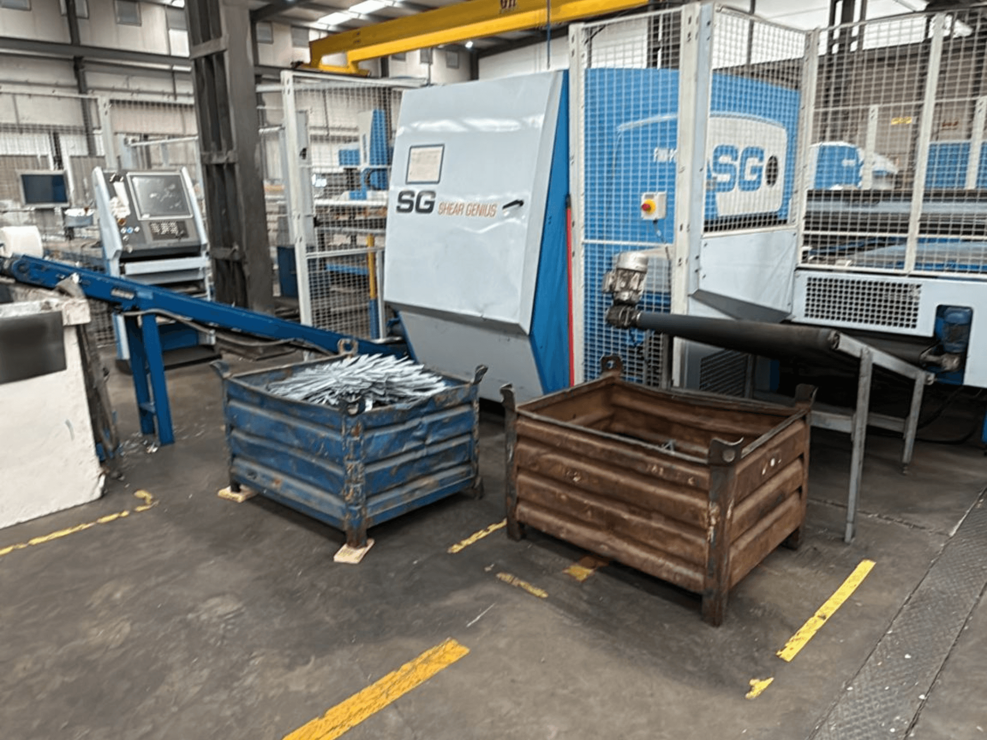 Punzonatrice e piegatrice Finn-Power SG6 12.61, vista frontale con contenitori metallici accanto in un'officina.