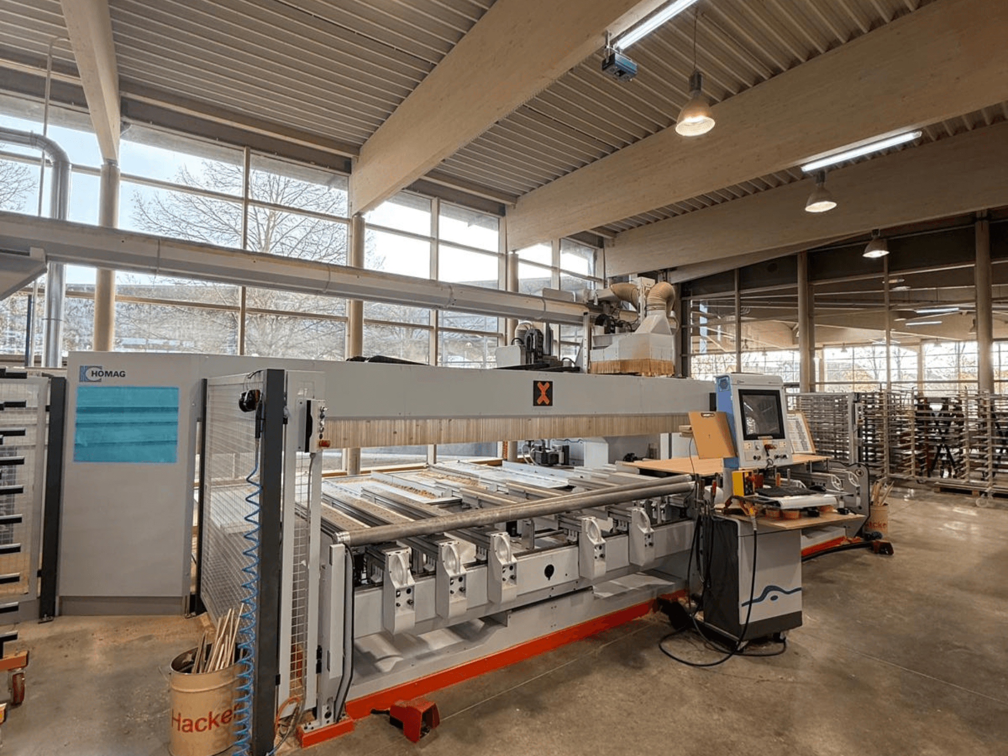 Macchina CNC HOMAG in un'officina, vista frontale, che mostra un pannello di controllo e molteplici slot per utensili per la lavorazione di precisione del legno.