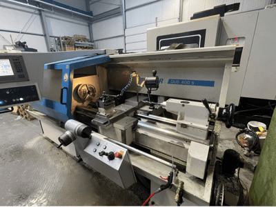 Tornio CNC DUS 400 ti visto frontalmente, con pannello di controllo, portautensili e area di lavoro illuminata.