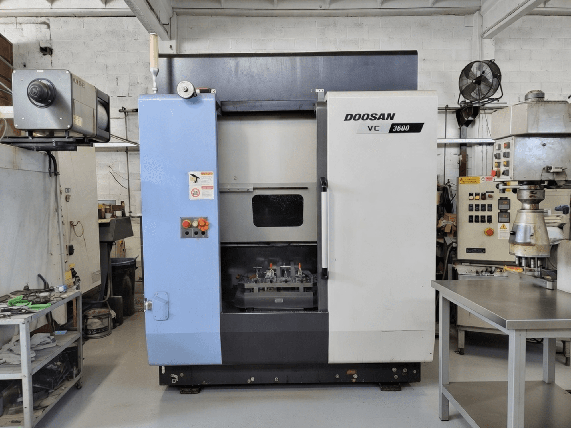 Centro di lavoro verticale DOOSAN VC 3600 in vista frontale, con pannello di controllo e porta aperta che rivela l'area di lavoro.