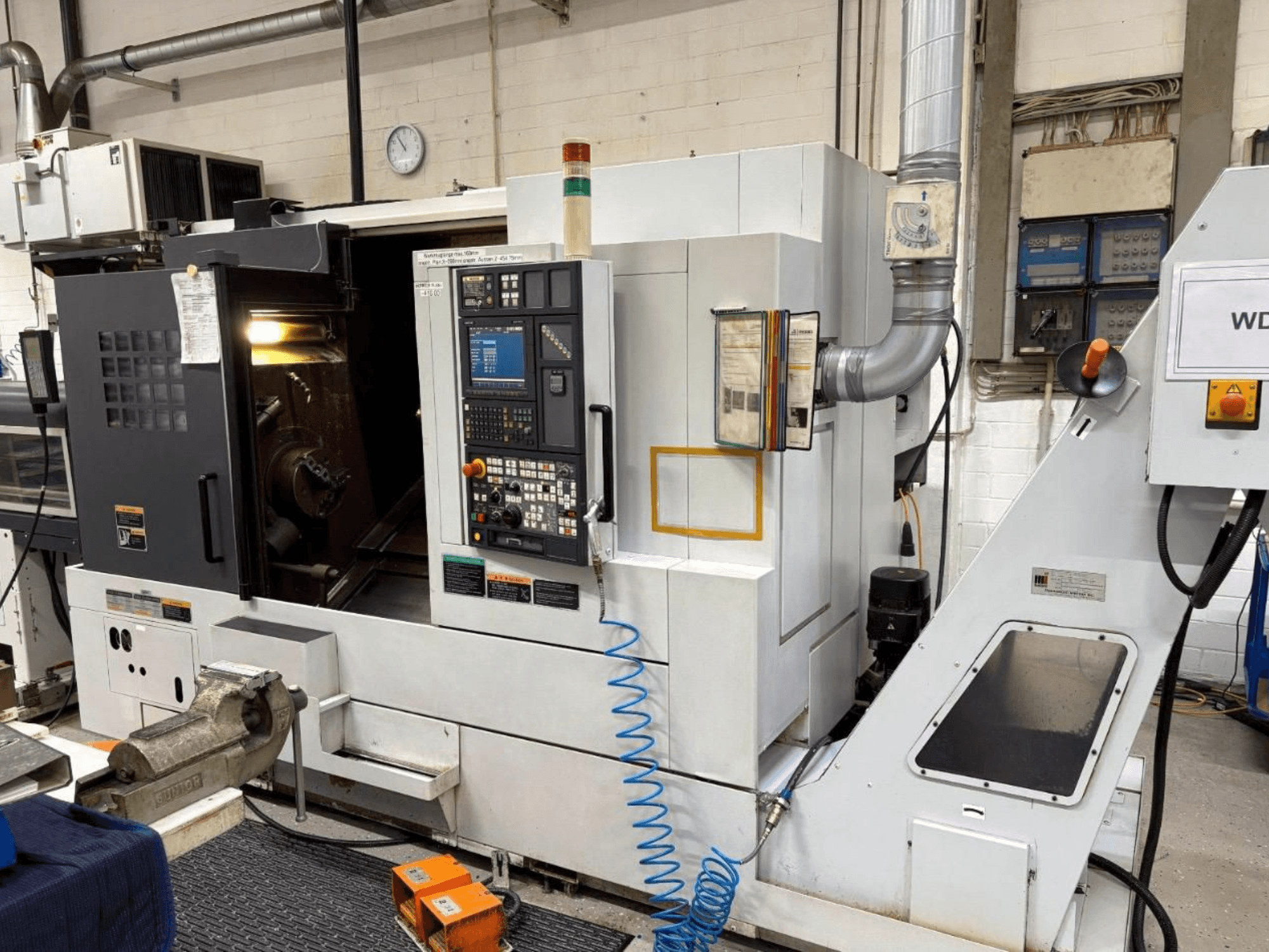 Centro di tornitura MORI SEIKI NL 2500 SY, vista frontale, con pannello di controllo e area di lavorazione. Sistema di raffreddamento e accessori visibili.
