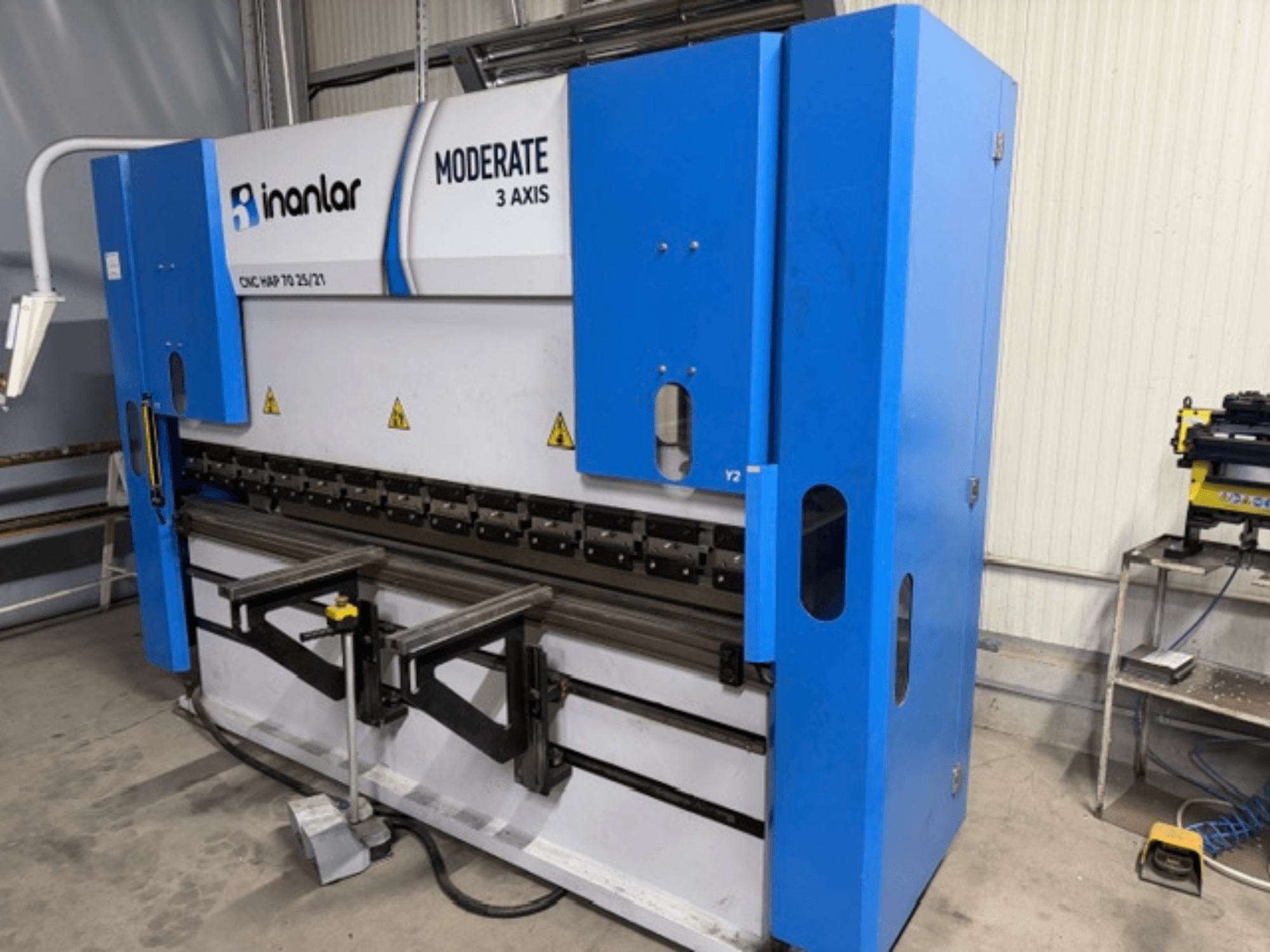 Macchina CNC Inanlar Moderate a 3 assi di colore blu, vista frontale, con leve di comando ed etichette di sicurezza visibili sul corpo.