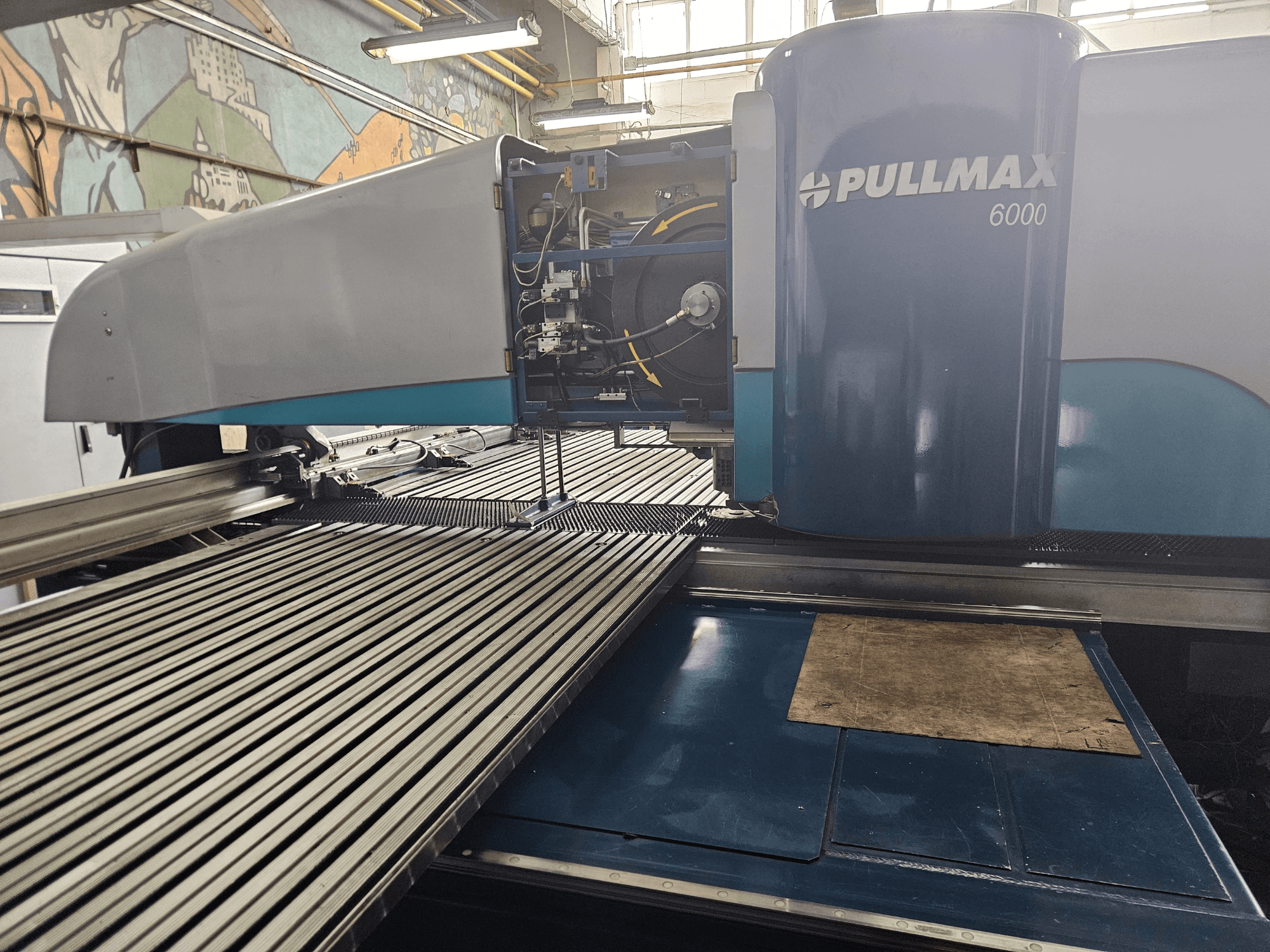 Vista frontale di una punzonatrice CNC Pullmax 6000, caratterizzata da un design elegante, un pannello operativo e una superficie di lavoro in metallo.