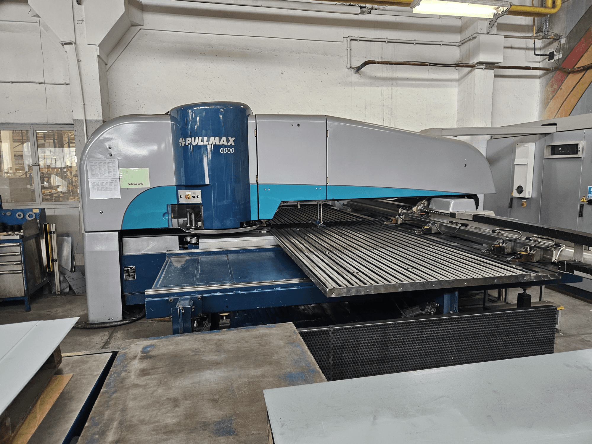 Vista frontale della punzonatrice CNC Pullmax 6000, che mostra il suo ampio pianale e la struttura metallica in un'officina.