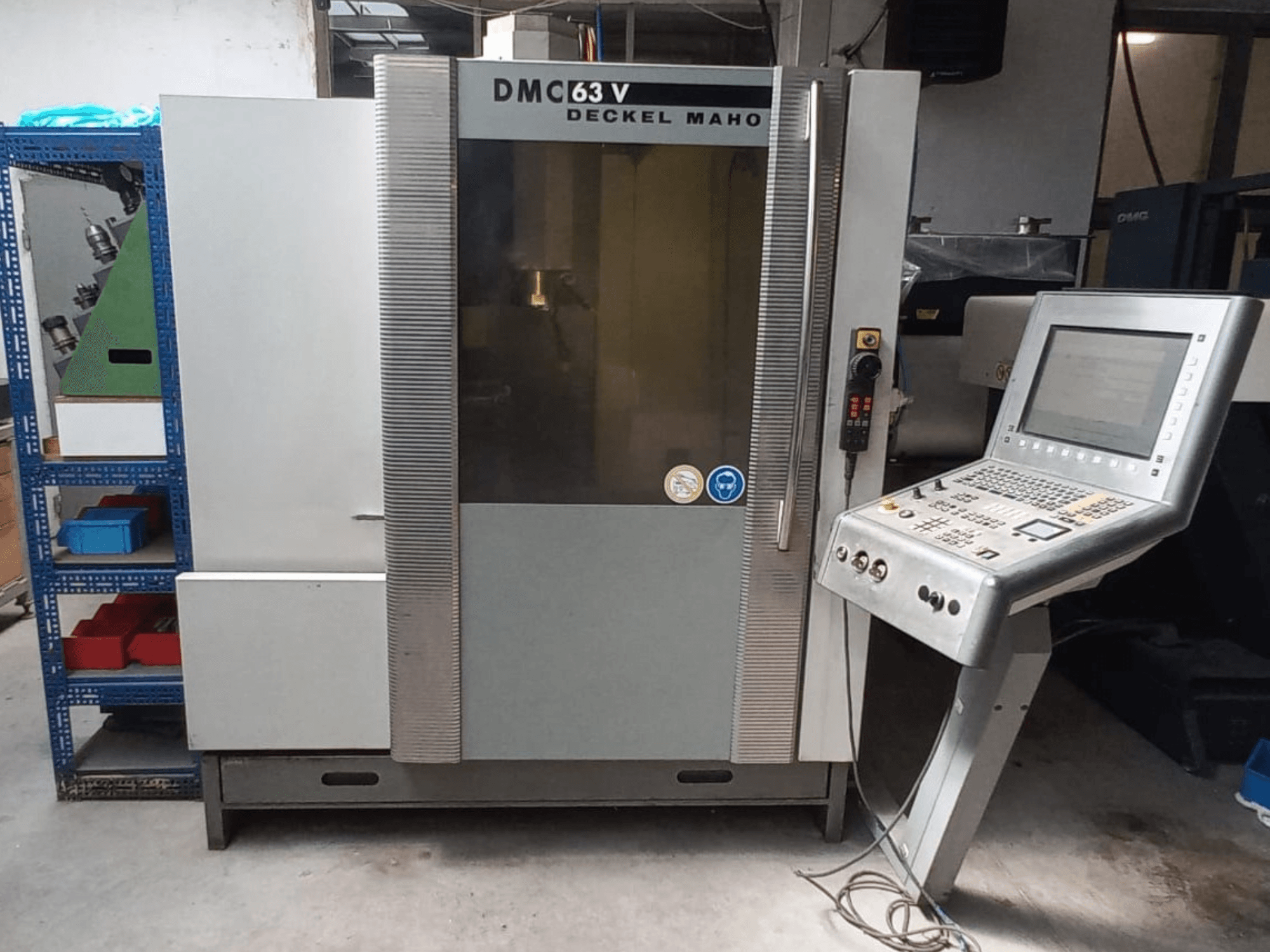 Vista frontale del centro di lavorazione verticale DMG DECKEL MAHO DMC 63V con pannello di comando e area di lavoro visibile.