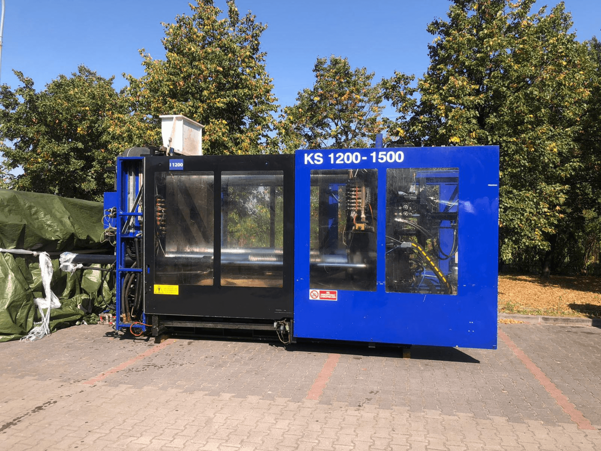 Pressa ad iniezione idraulica ITALTECH KS 1200 8300 ES, vista laterale, che mostra i comandi e i dettagli della macchina in un parco.