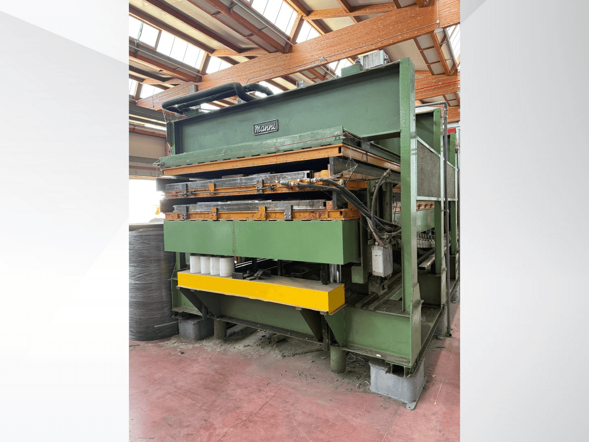 Pressa idraulica Manni, vista laterale, con corpo in metallo verde, base gialla e molteplici linee idrauliche visibili.