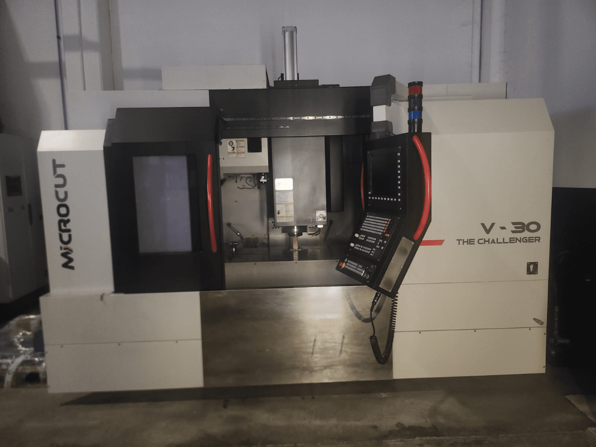 Microcut V-30 La macchina CNC Challenger, vista frontale, con pannello di controllo, area di taglio ed elementi di design industriale.