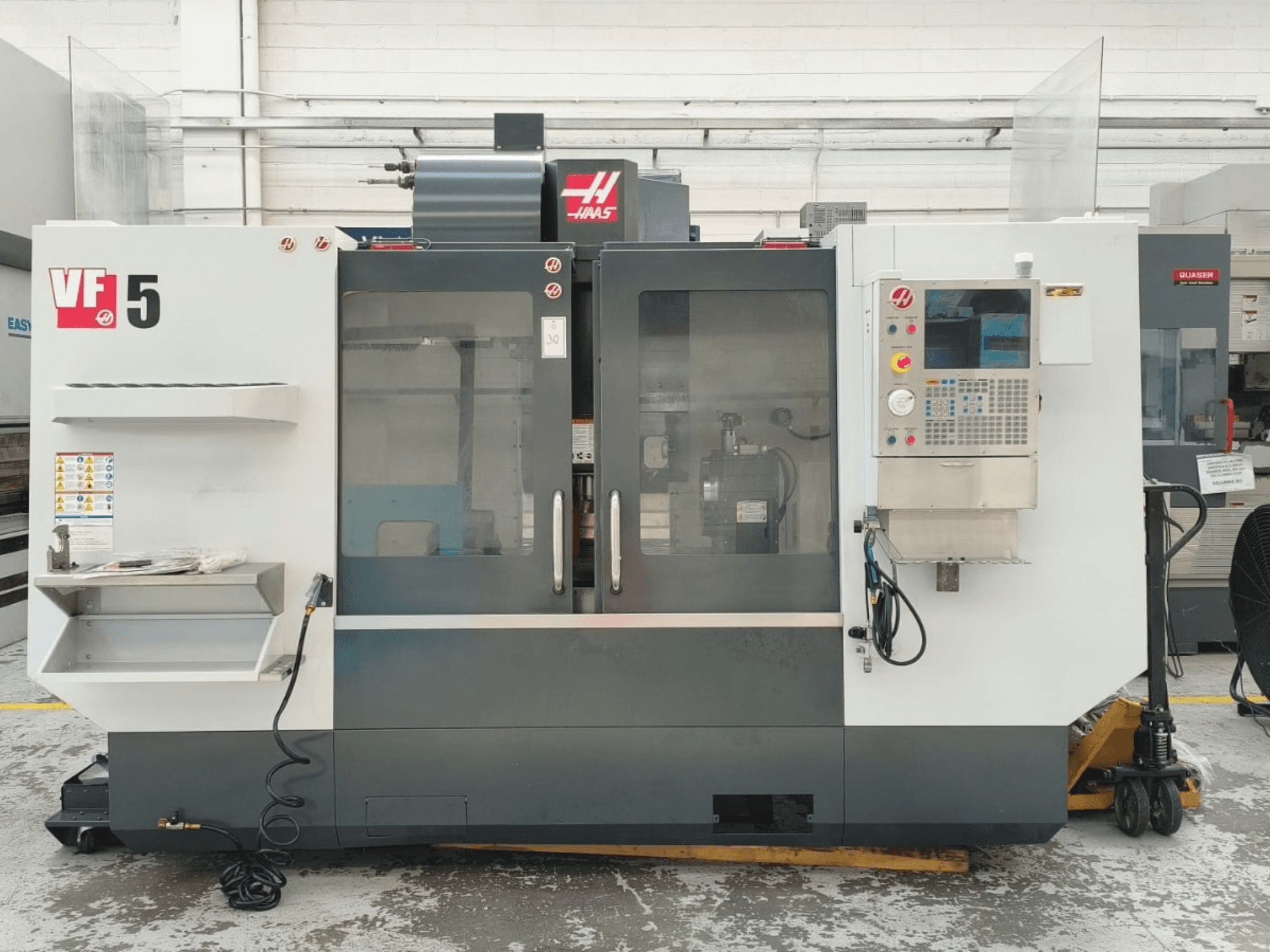 Vista frontale del centro di lavorazione verticale HAAS VF 5/40, con pannello di controllo e porte in vetro.