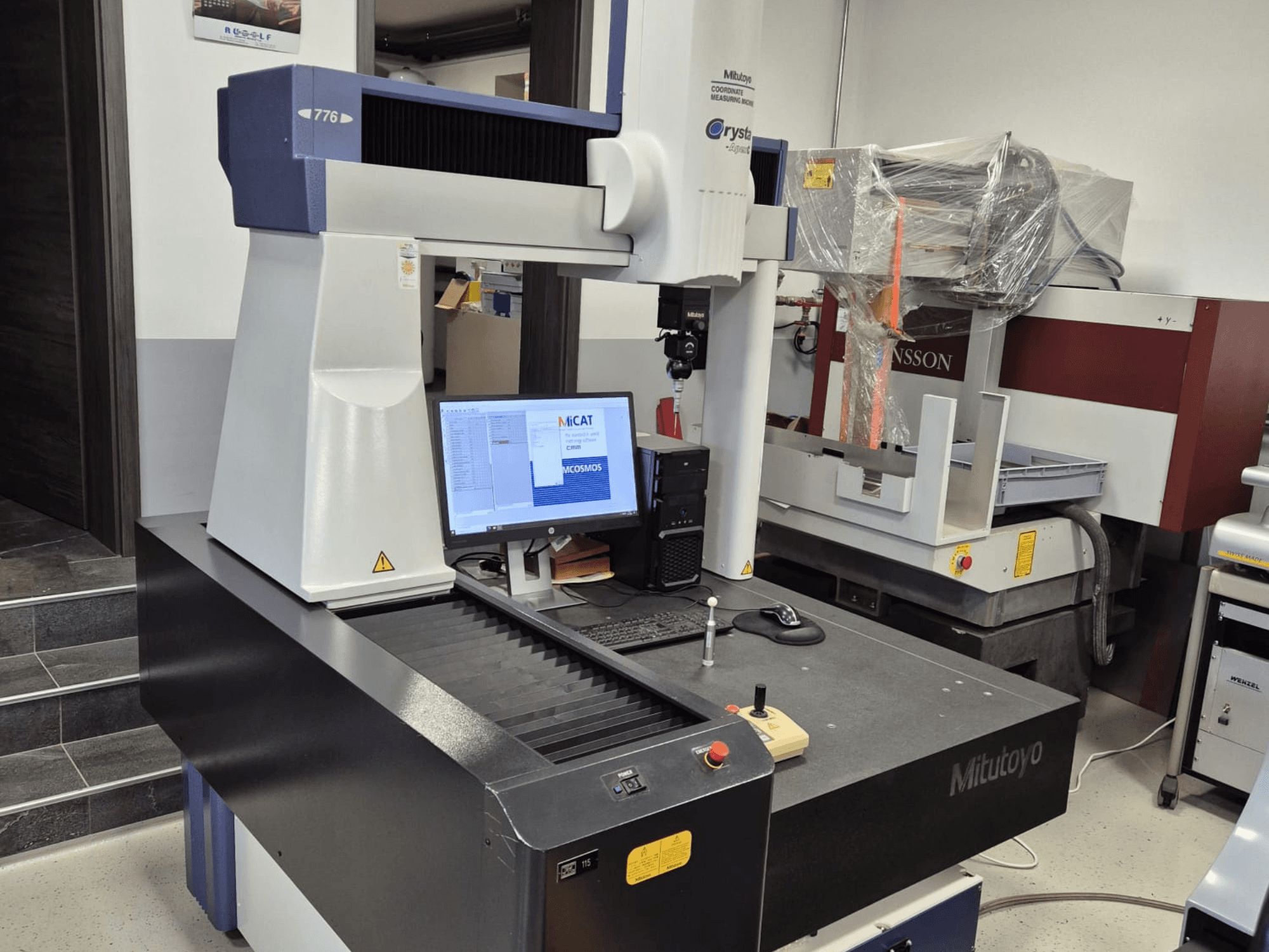 Macchina di misura a coordinate Mitutoyo modello 776 in vista frontale, con un monitor che visualizza il software di misura e i comandi visibili.