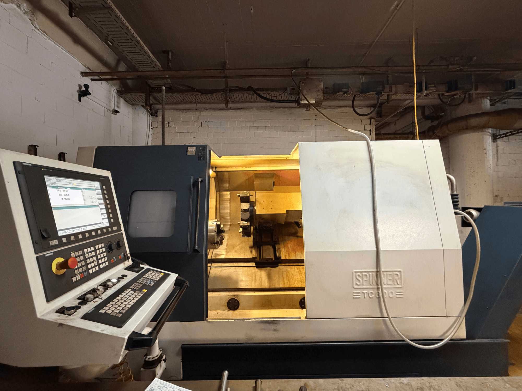 Tornio orizzontale SPINNER TC800 in un'officina, con pannello di controllo e componenti interni a vista.