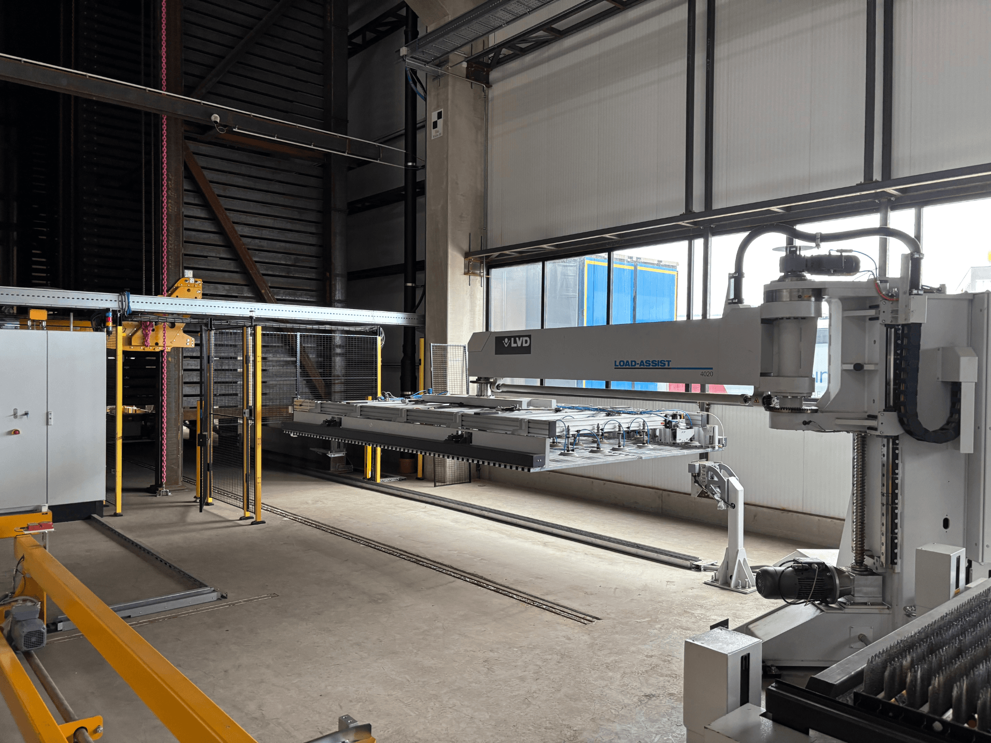 L'apparecchiatura di automazione LVD Load-Assist 4020 in una vista frontale con un braccio robotico e un sistema di carico visibili in un ampio spazio di lavoro.