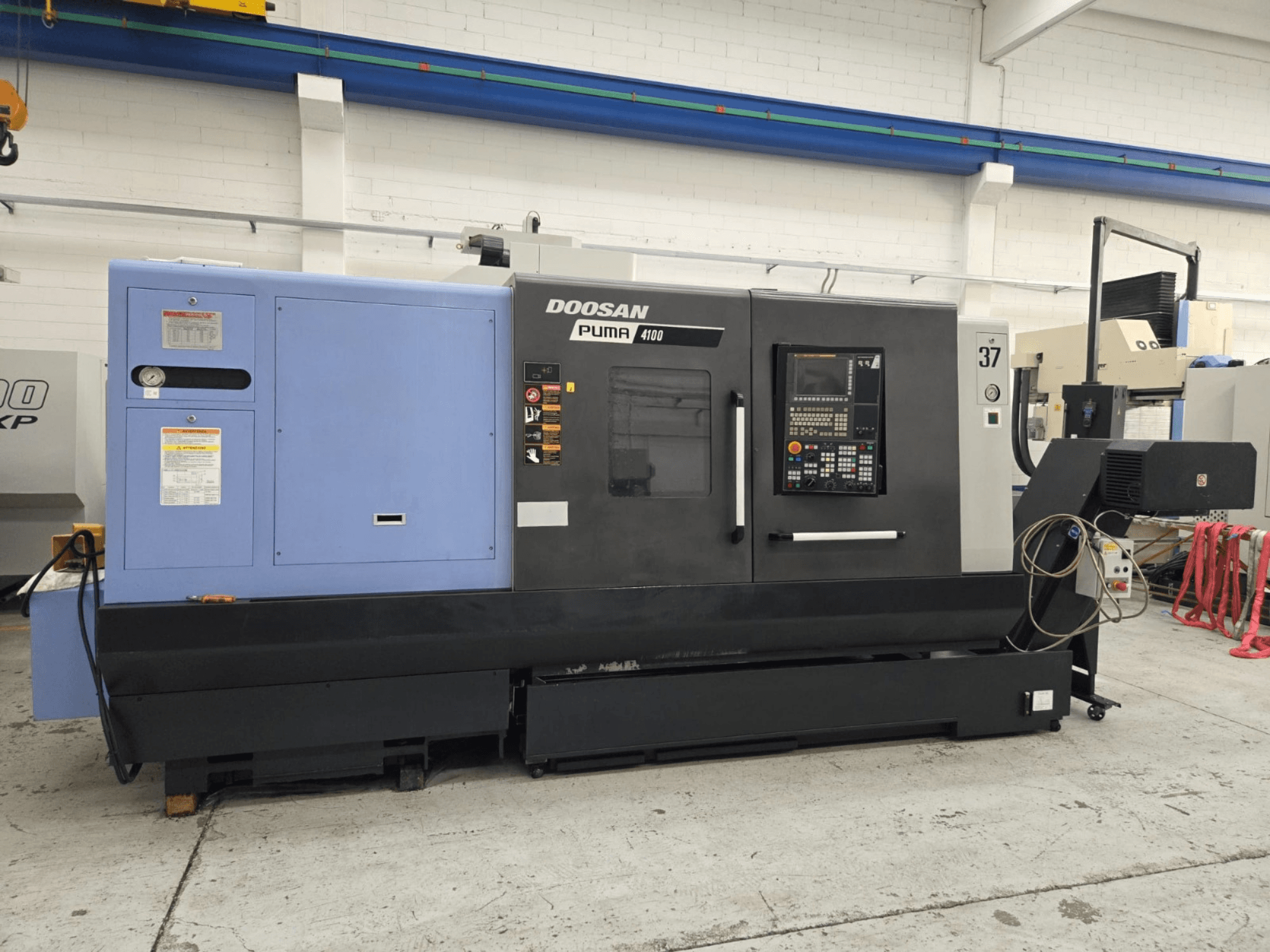 Tornio CNC Doosan Puma 4100, vista frontale; dispone di pannello di controllo, unità di potenza blu ed etichette dettagliate per la guida operativa.