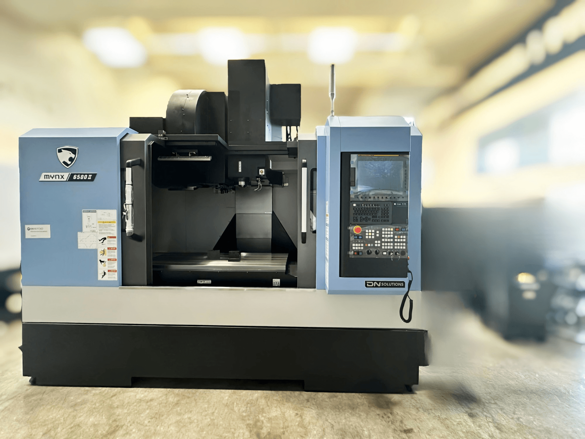 Centro di lavorazione verticale DN SOLUTIONS MYNX 6500 II, vista frontale che mostra il pannello di controllo e l'area di lavoro.