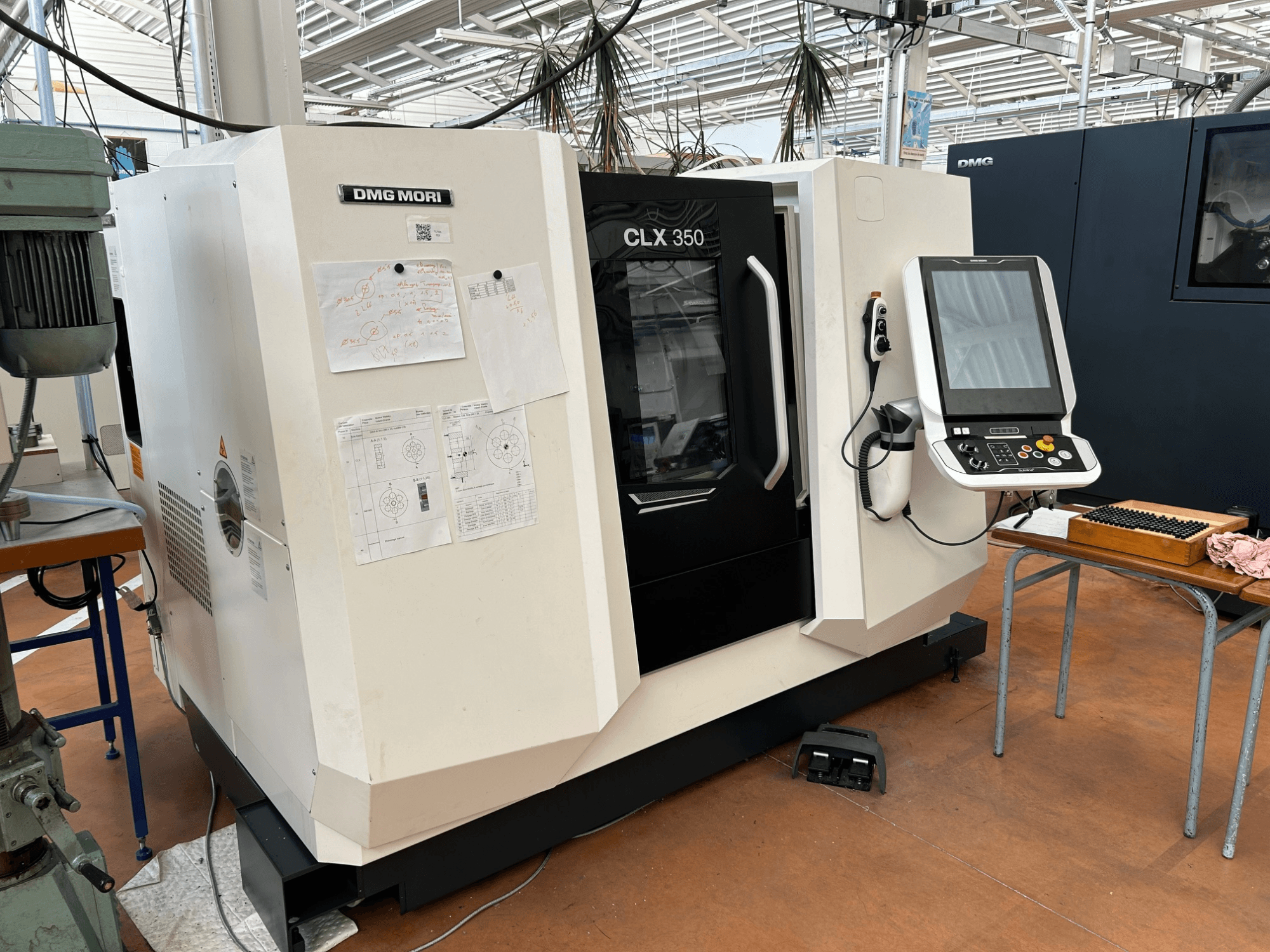 Tornio orizzontale DMG MORI CLX 350 V4, vista frontale con pannello di controllo e documentazione tecnica allegata.