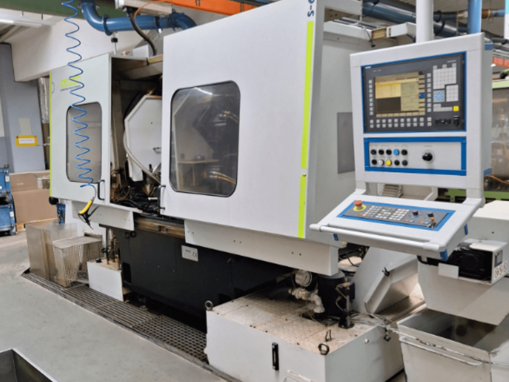 Fresatrice industriale con pannello di controllo, vista laterale, con camere doppie e connessioni visibili alle tubazioni.