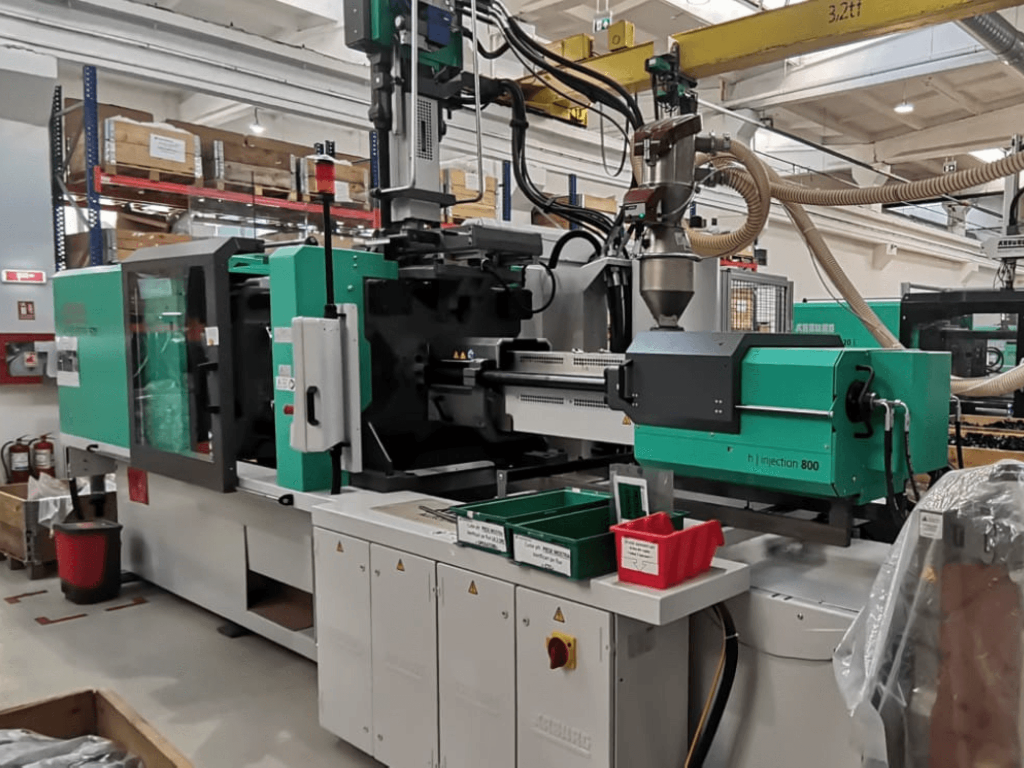 Macchina H a iniezione 800 in una fabbrica, vista frontale, caratterizzata da un design verde e nero, con pannelli di controllo e contenitori per i pezzi.
