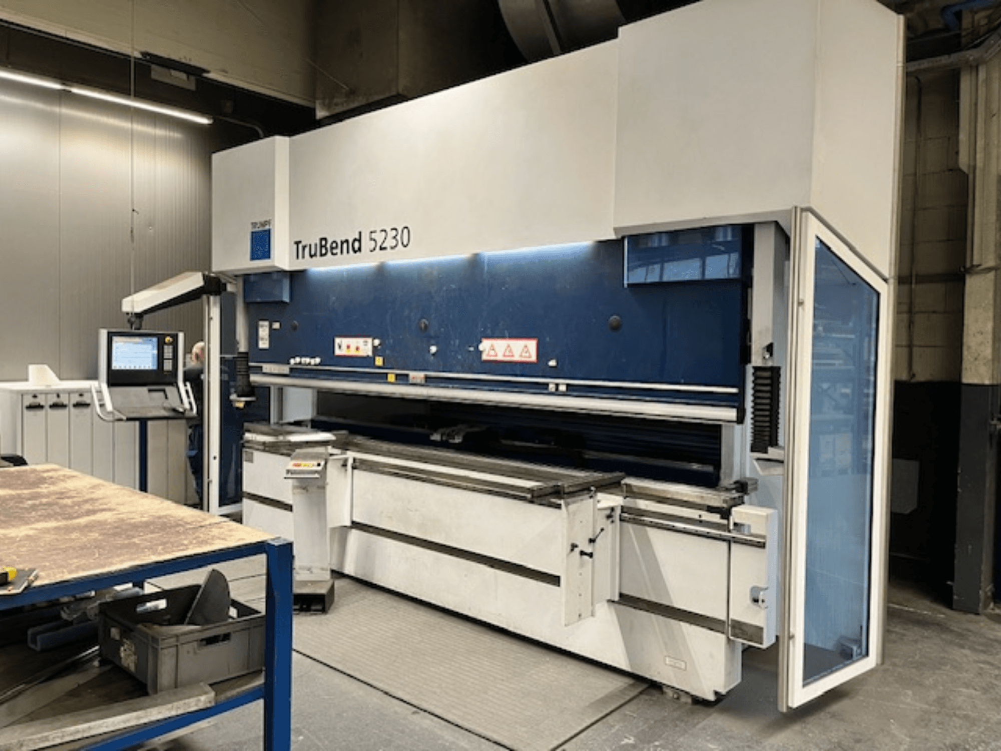 Curvatrice TruBend 5230 in ambiente industriale; vista frontale che mostra il pannello di controllo, le funzioni di sicurezza e il tavolo di lavoro.