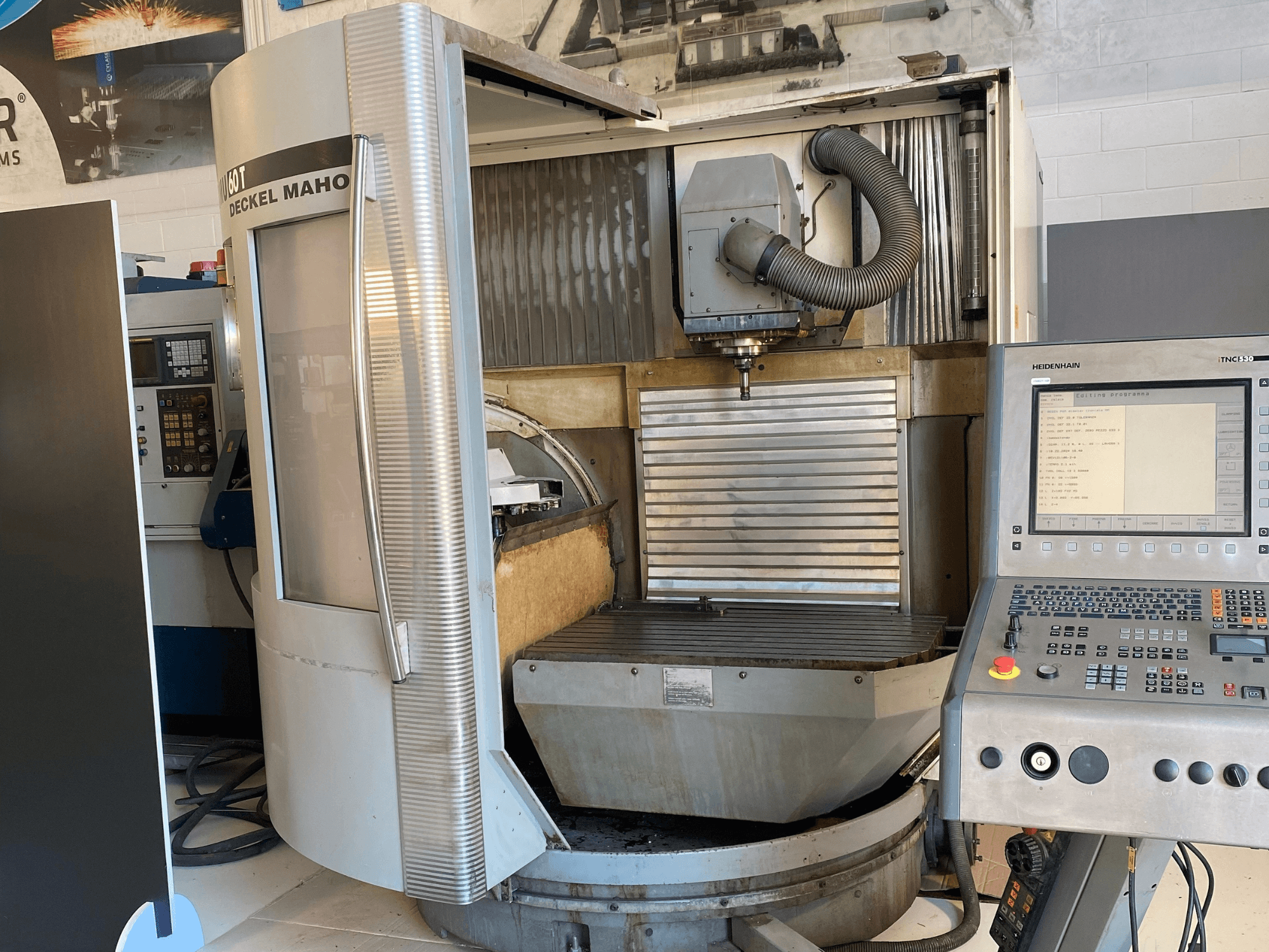 Vista frontale di una fresatrice DECKEL MAHO DMU 60T con pannello di controllo, mandrino e tavola di fresatura visibili.