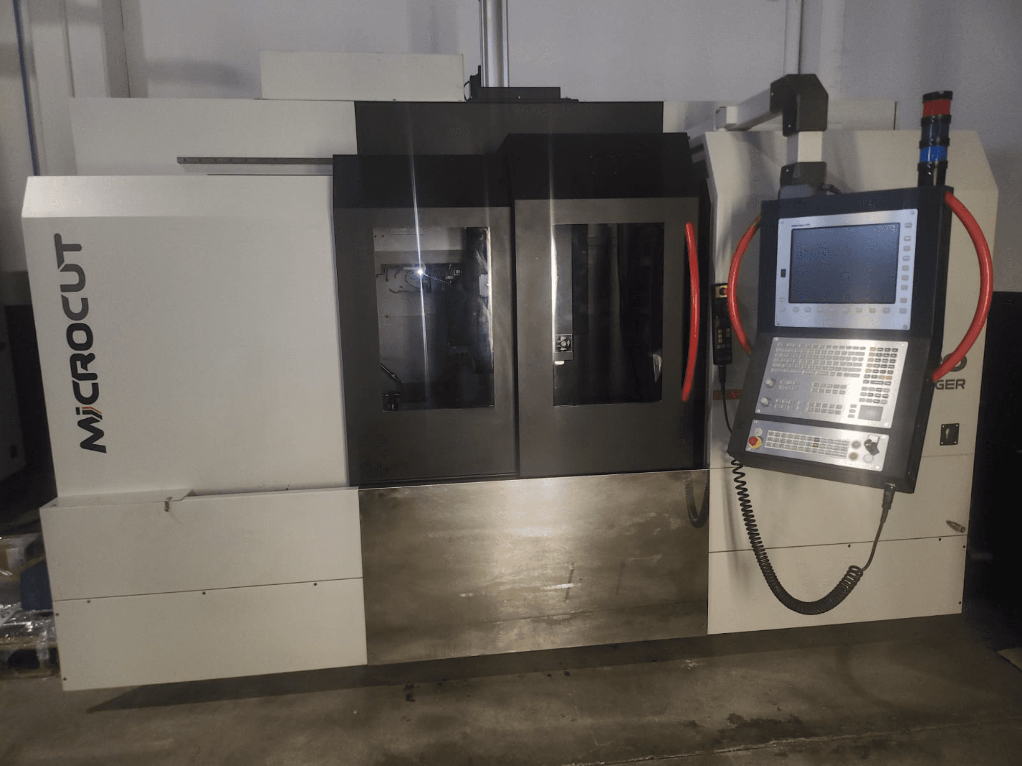 Macchina CNC Microcut vista dal davanti; presenta pannello di controllo, doppie finestre, design industriale e finitura metallica.