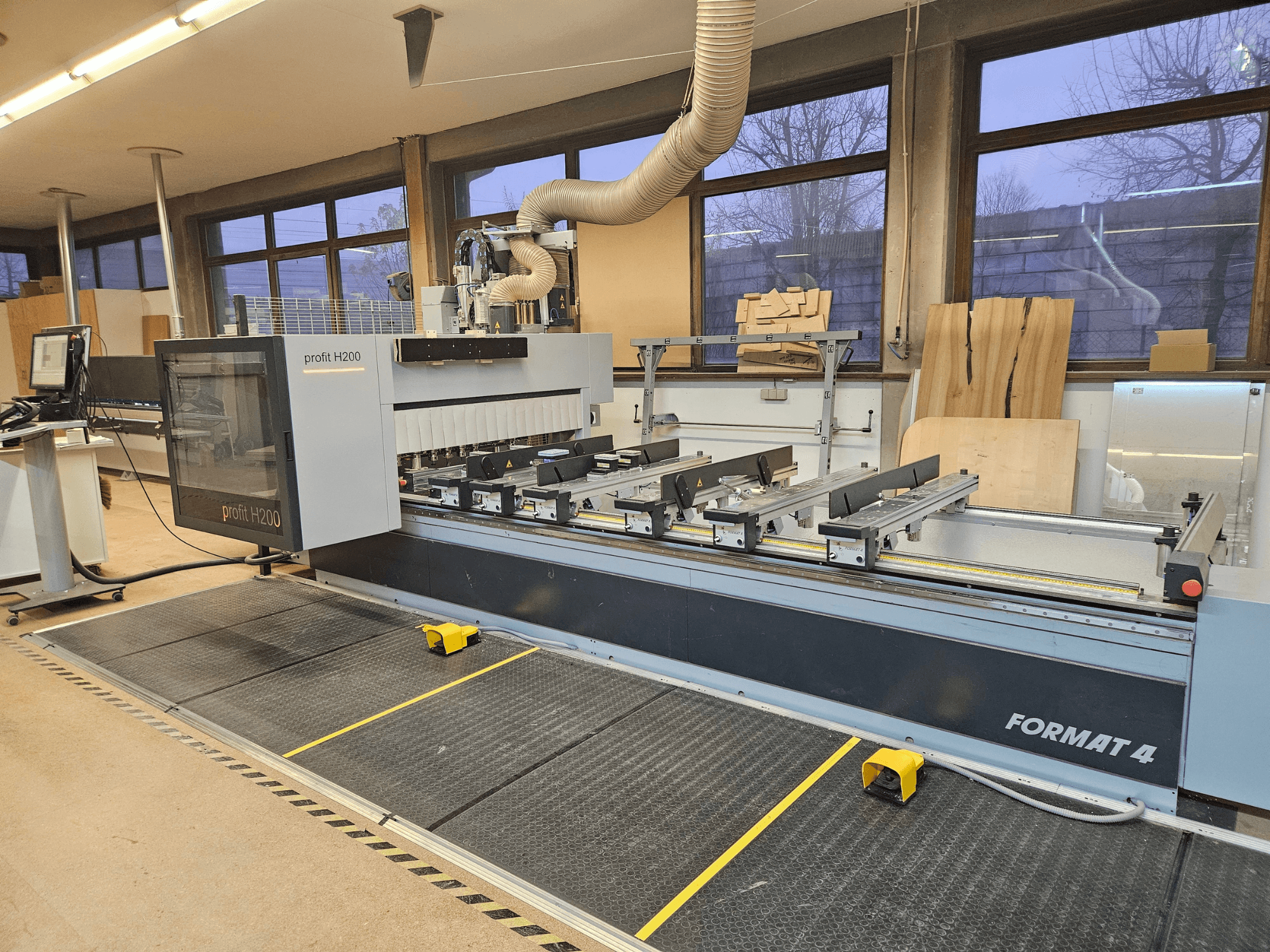 Formato 4 profitto Macchina CNC H200, vista frontale, con banco di taglio, pannello di controllo e sistema di aspirazione della polvere visibili.