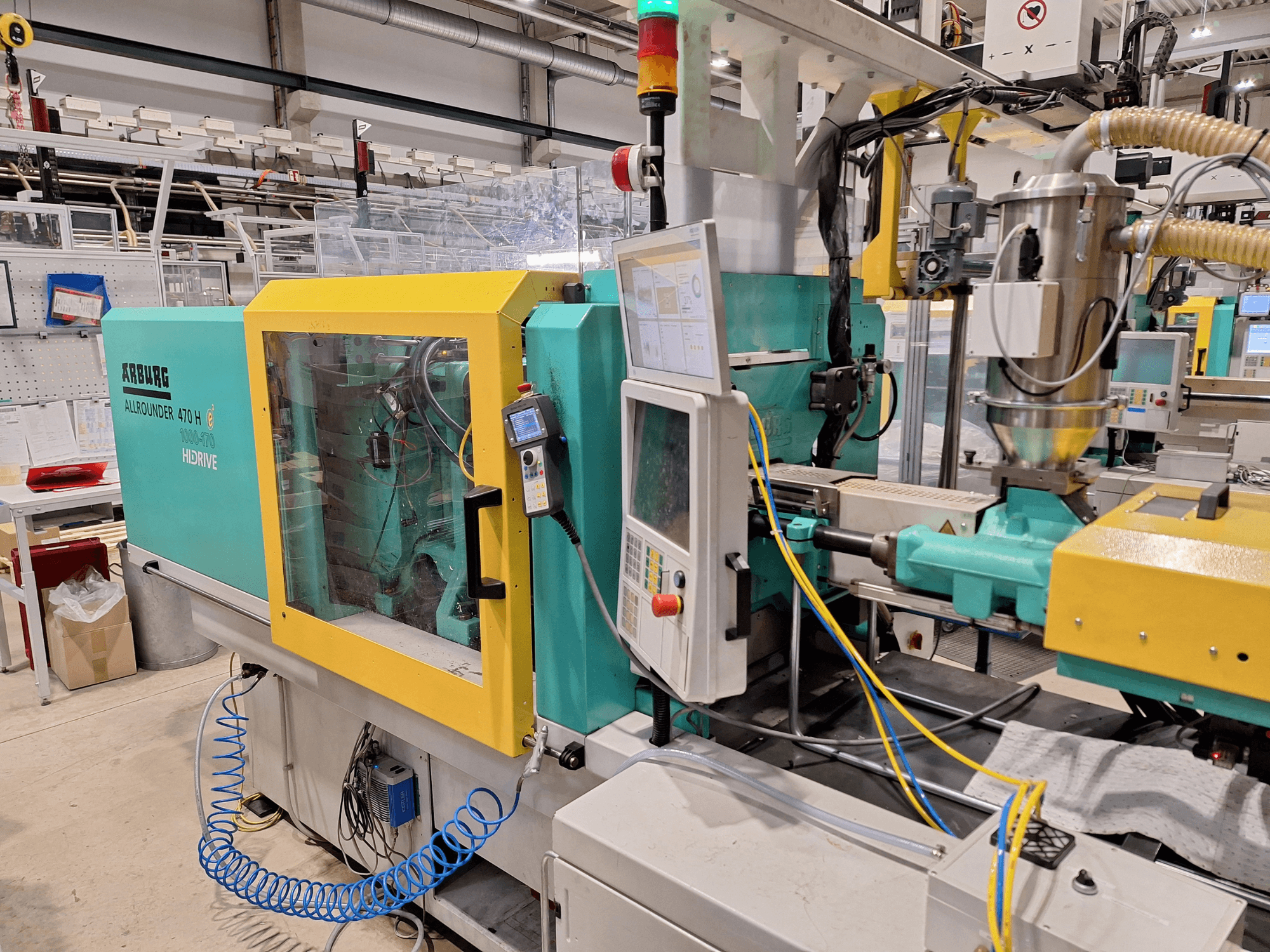 Pressa a iniezione idraulica Arburg 470 H 1000-170, vista laterale che mostra il pannello di controllo e il sistema di alimentazione.