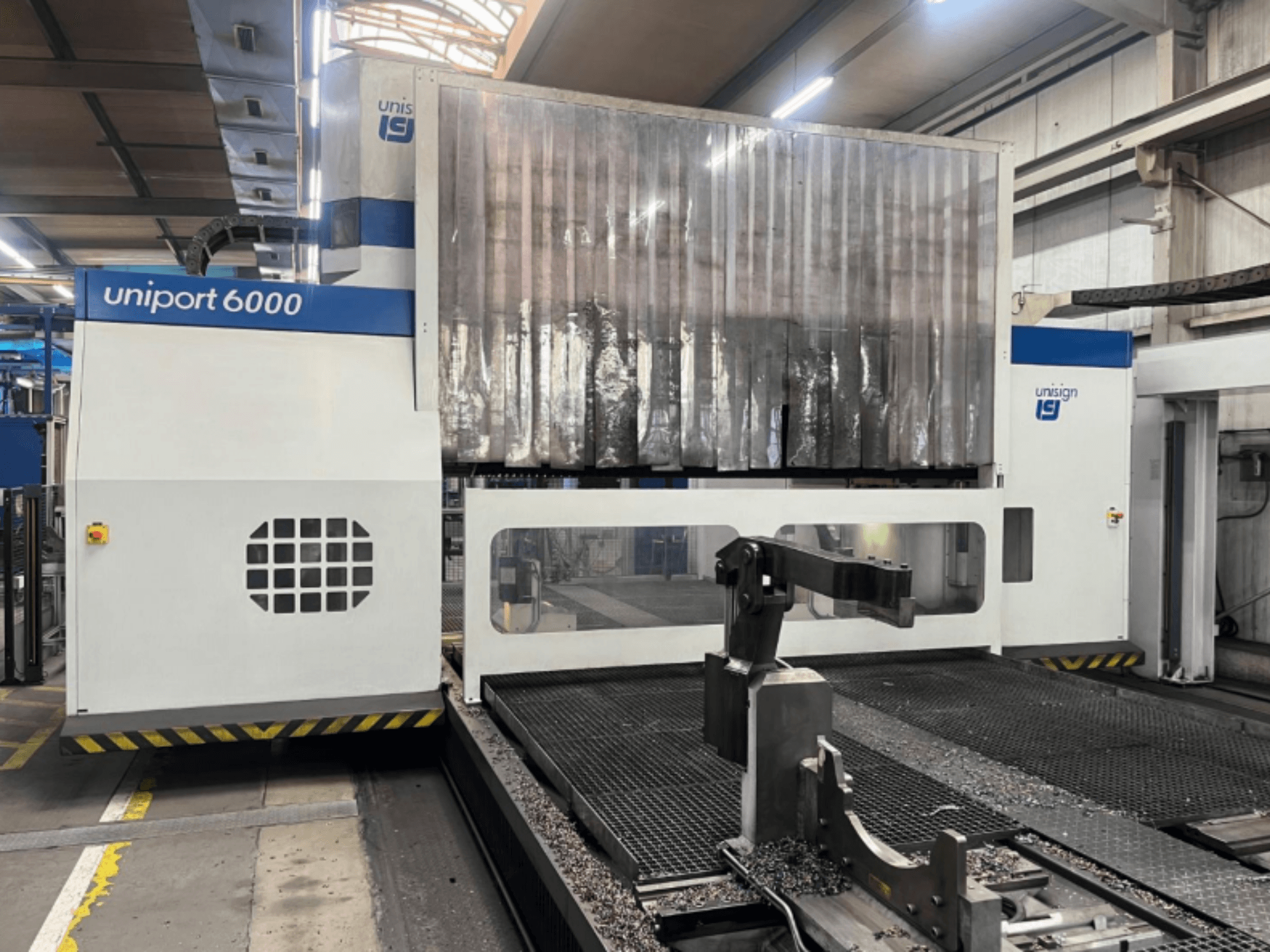 Fresatrice a portale Unisign uniport 6000, vista frontale, che mostra la struttura della macchina e l'area di taglio con trucioli di metallo.