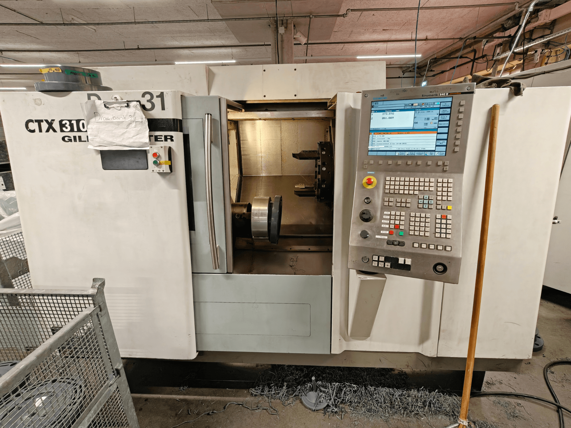 Tornio orizzontale CTX 310 di Gildemeister, vista frontale con pannello di controllo, che mostra gli utensili e lo spazio di lavoro interno.