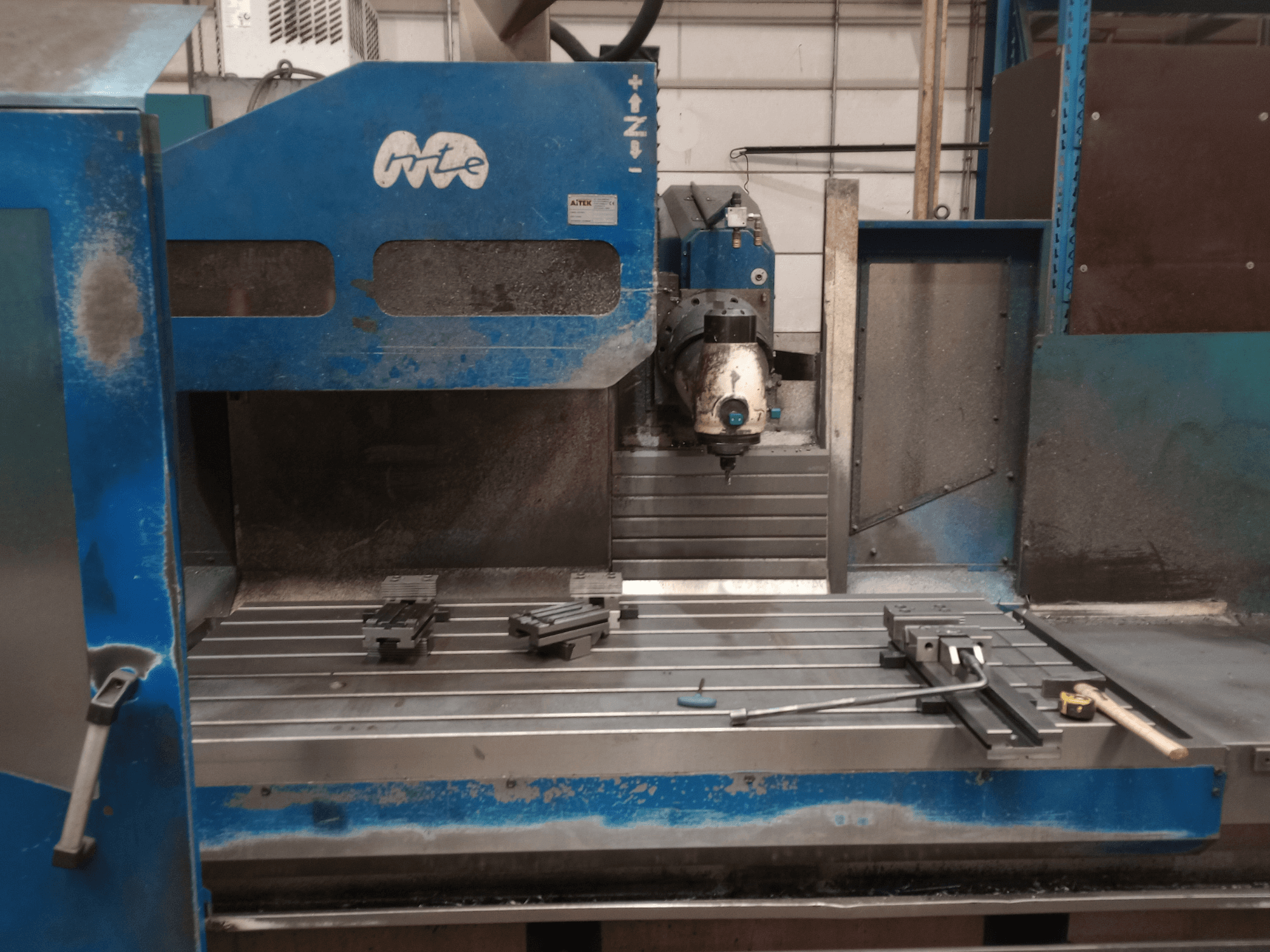 Fresatrice a bancale MTE BF 2200, vista frontale, che mostra il piano di lavoro con i dispositivi di fissaggio e la testa di taglio.