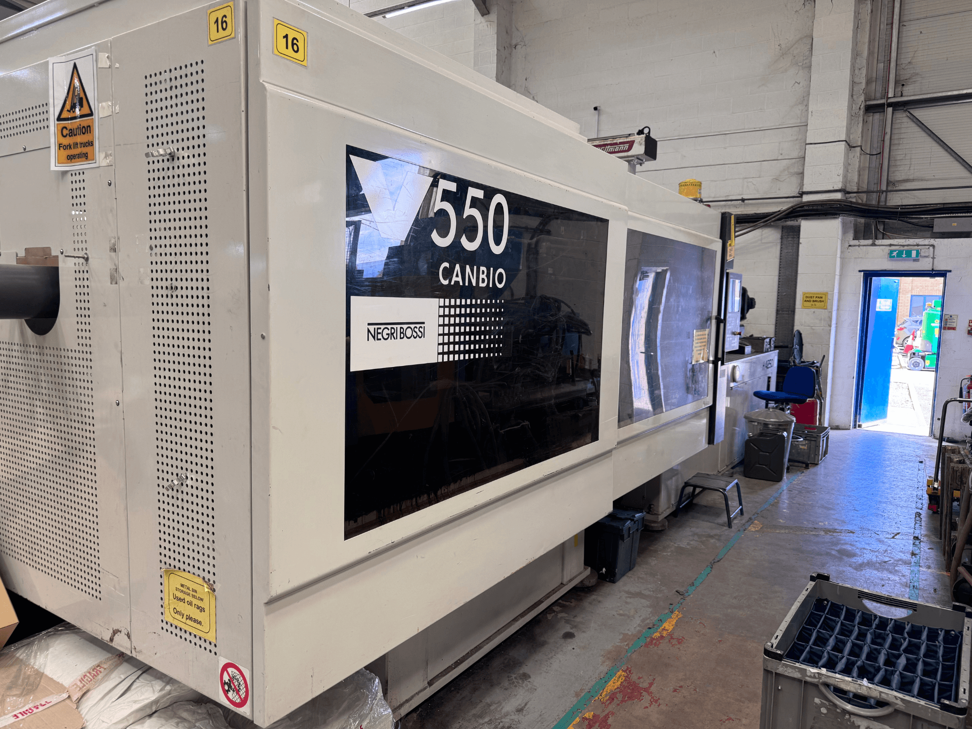 Macchina per lo stampaggio a iniezione idraulica Negri Bossi 5500H-4250, vista frontale che mostra il pannello di controllo e i segnali di avvertimento.