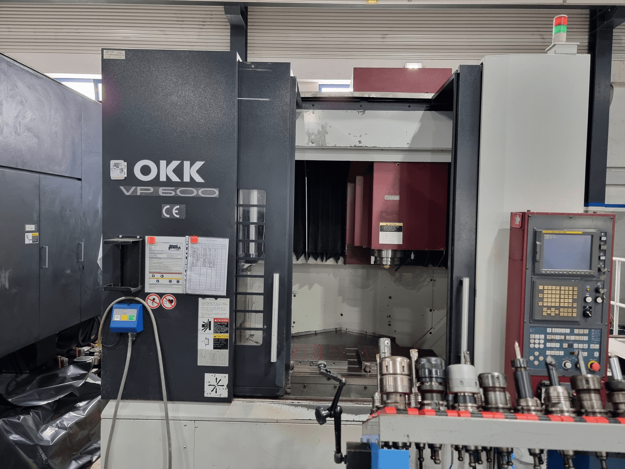 Centro di lavorazione verticale OKK VP600 visto di fronte, con in primo piano il pannello di controllo e i portautensili montati su una cremagliera.