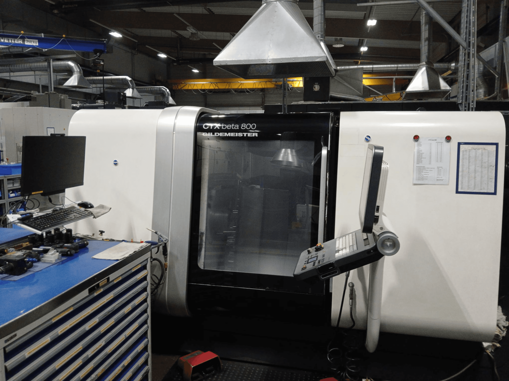 Tornio orizzontale DMG CTX beta 800, vista frontale con pannello di controllo e monitor accanto a una postazione di lavoro.