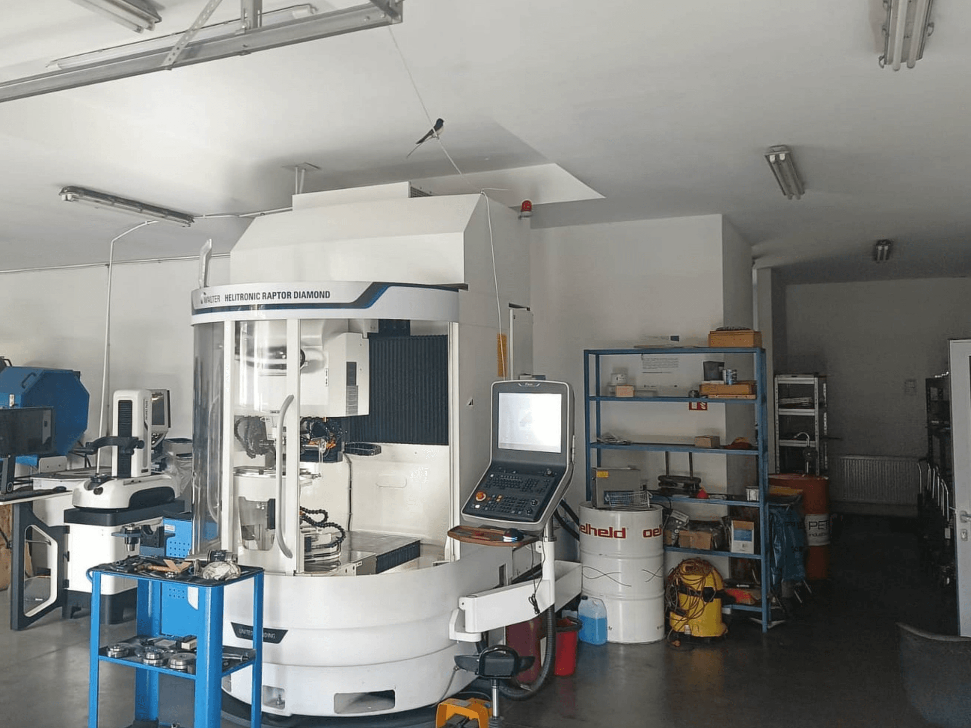 Rettificatrice cilindrica WALTER HELITRONIC RAPTOR DIAMOND in un’officina, vista laterale con pannello di controllo e utensili nelle vicinanze.