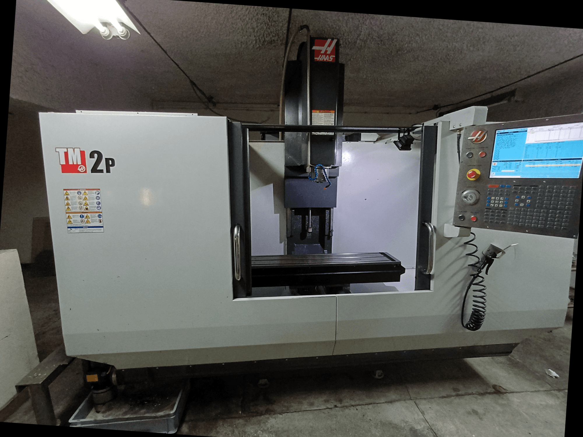 Centro di lavoro verticale HAAS TM-2P, vista frontale, con pannello di controllo, testa del mandrino e basamento della macchina.