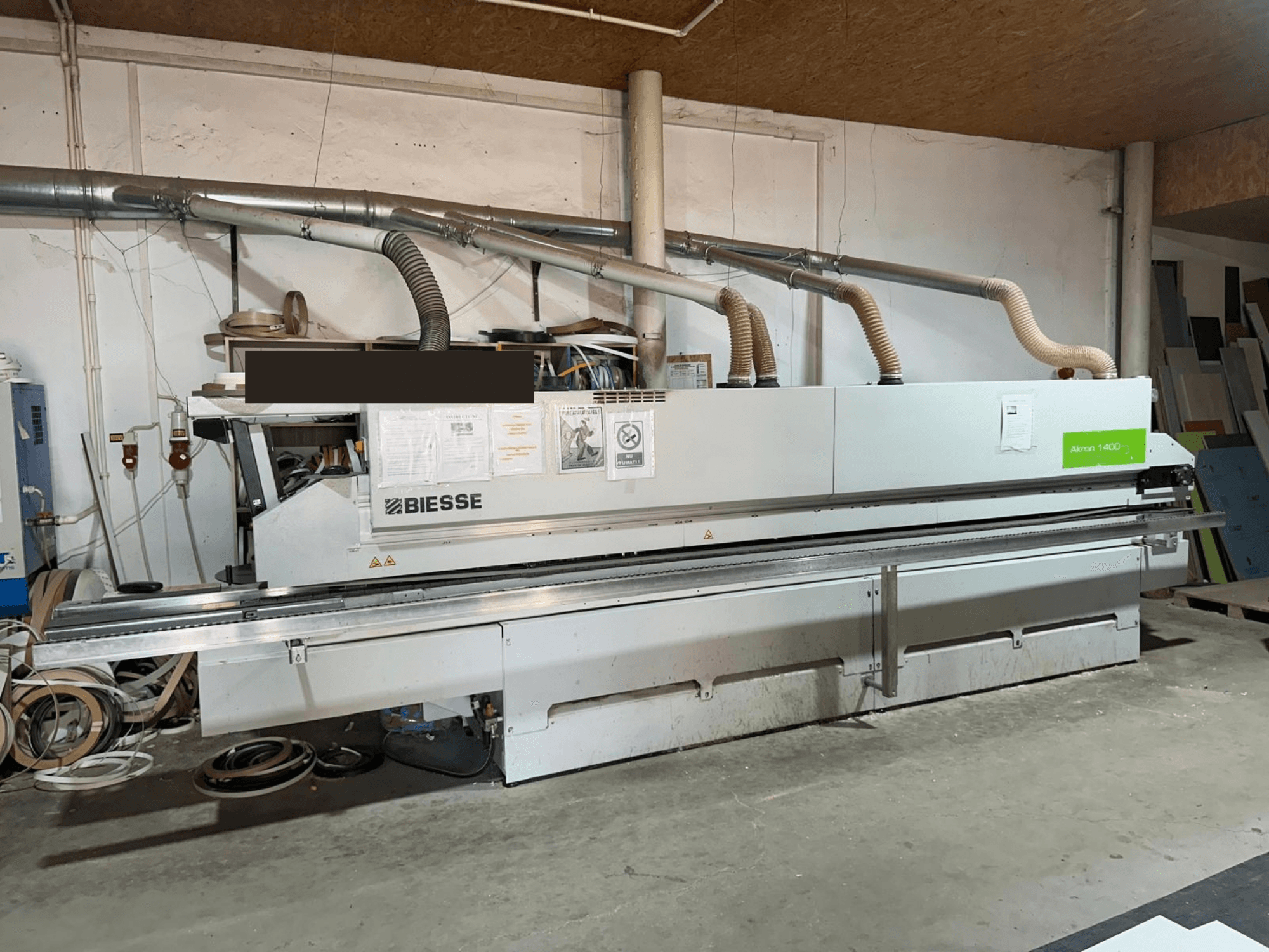Bordatrice BIESSE AKRON 1440 A, vista frontale, con pannello di comando e componenti per l'aspirazione delle polveri ben visibili in un ambiente di officina.