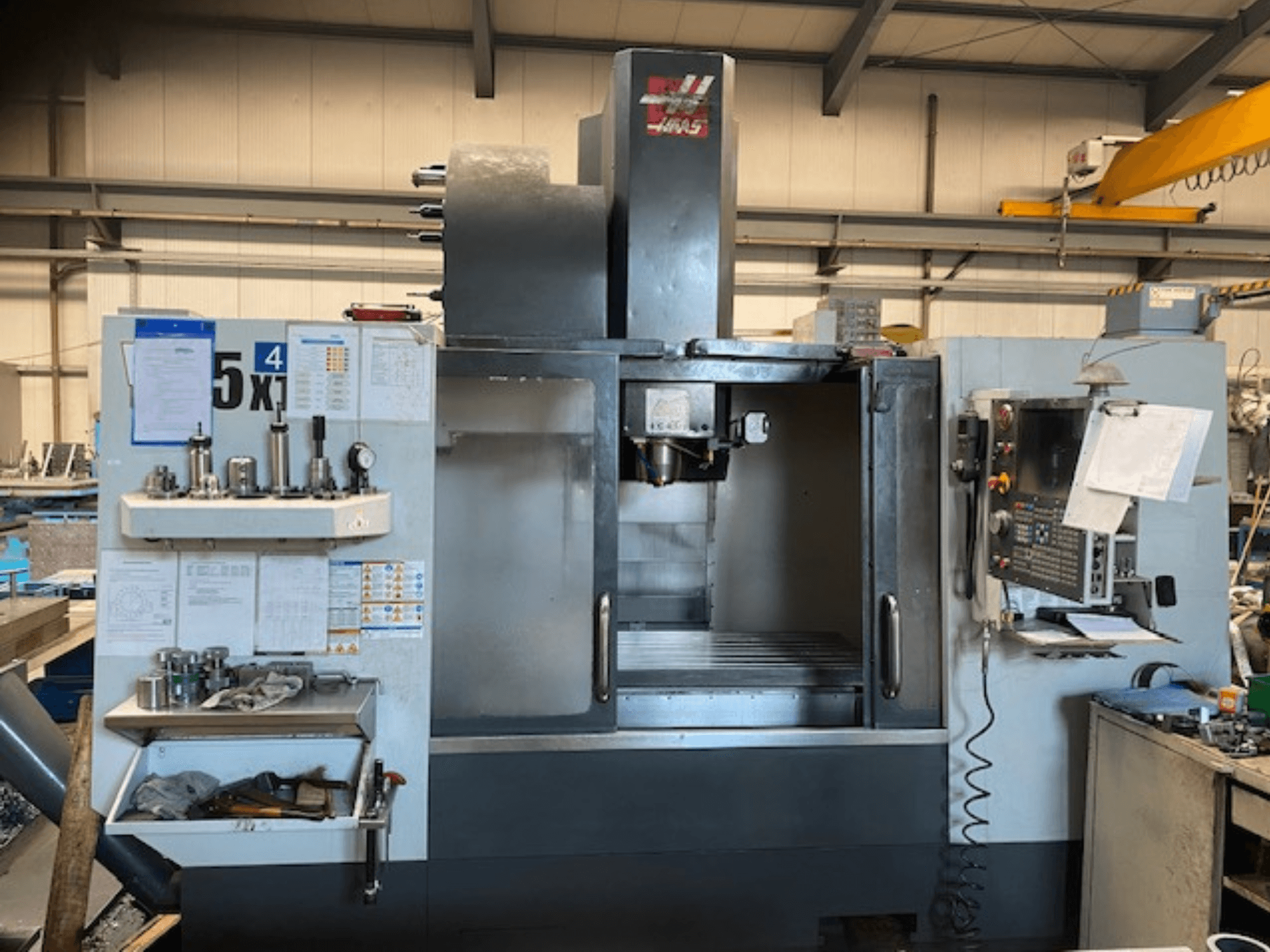 Centro di lavoro verticale Haas VF-5, vista frontale, che mostra il pannello di controllo, il magazzino utensili e l'area del mandrino.