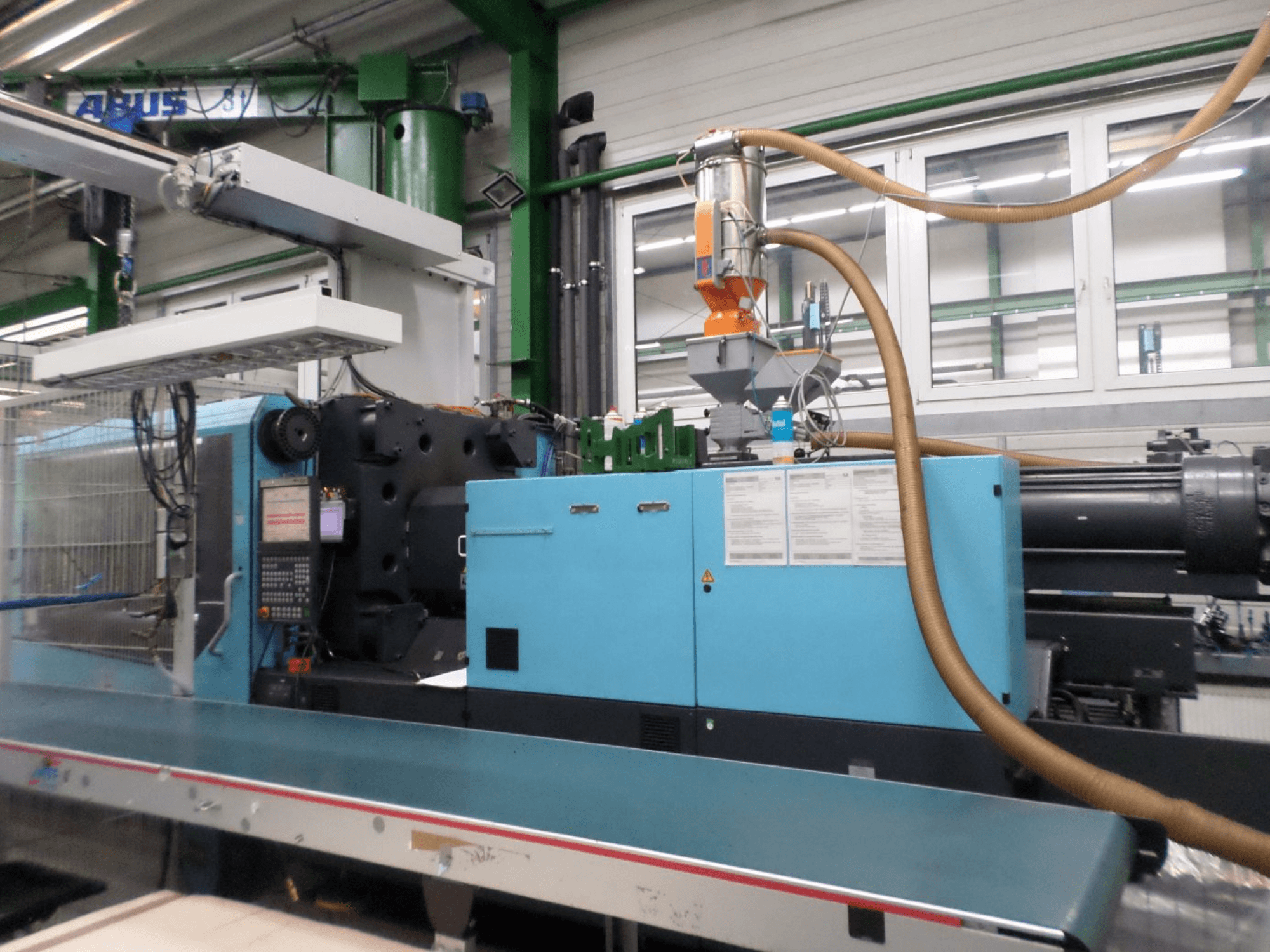 Vista frontale di una pressa a iniezione idraulica DEMAG D 420, con pannello di controllo, tramoggia e componenti idraulici.