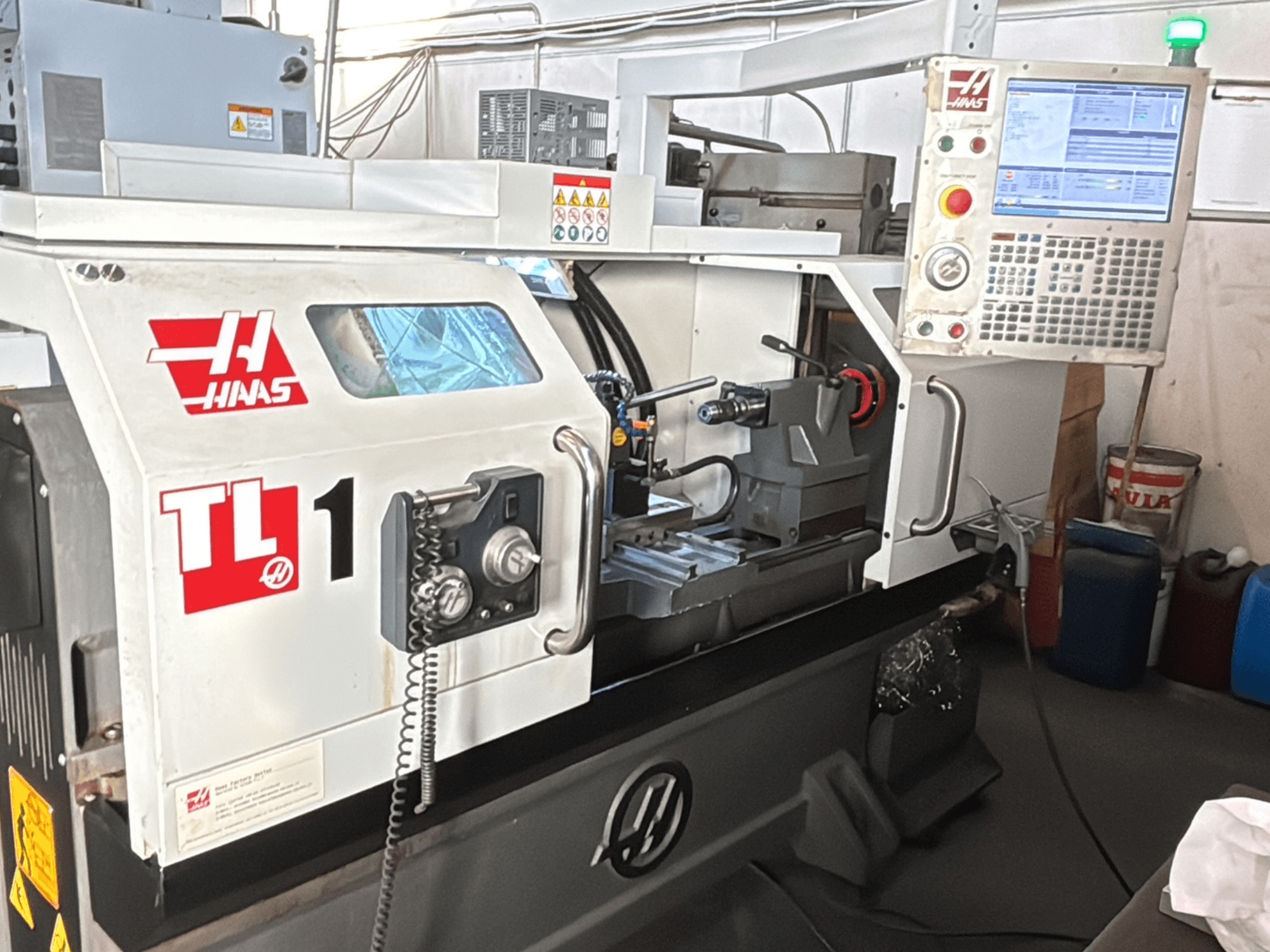 Tornio CNC Haas TL-1, vista frontale, pannello di controllo con display, portautensili ed etichette di sicurezza.