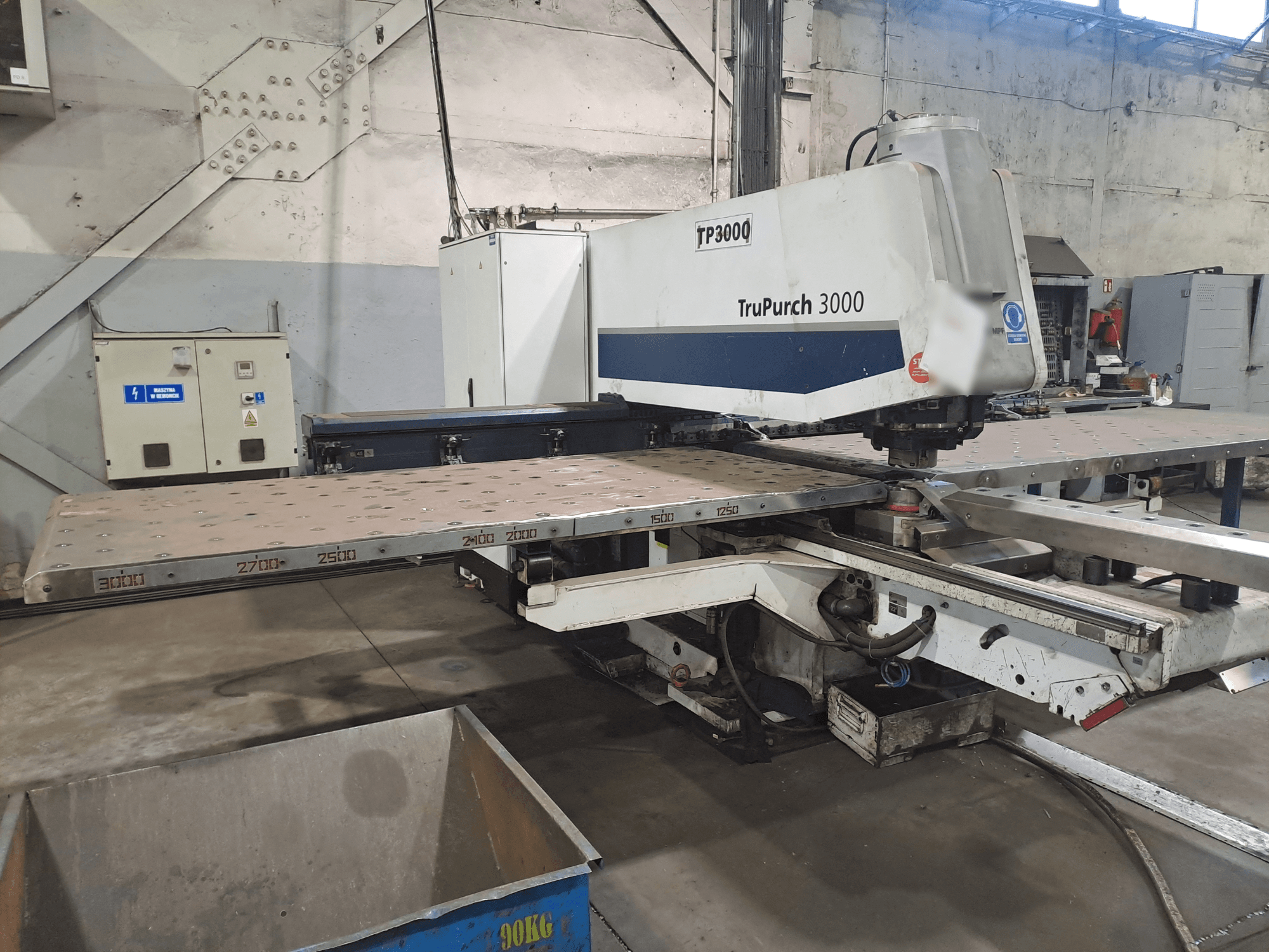 Macchina TruPunch 3000 CNC vista dal davanti, con una grande piastra metallica e marcature di misura, in un ambiente industriale.