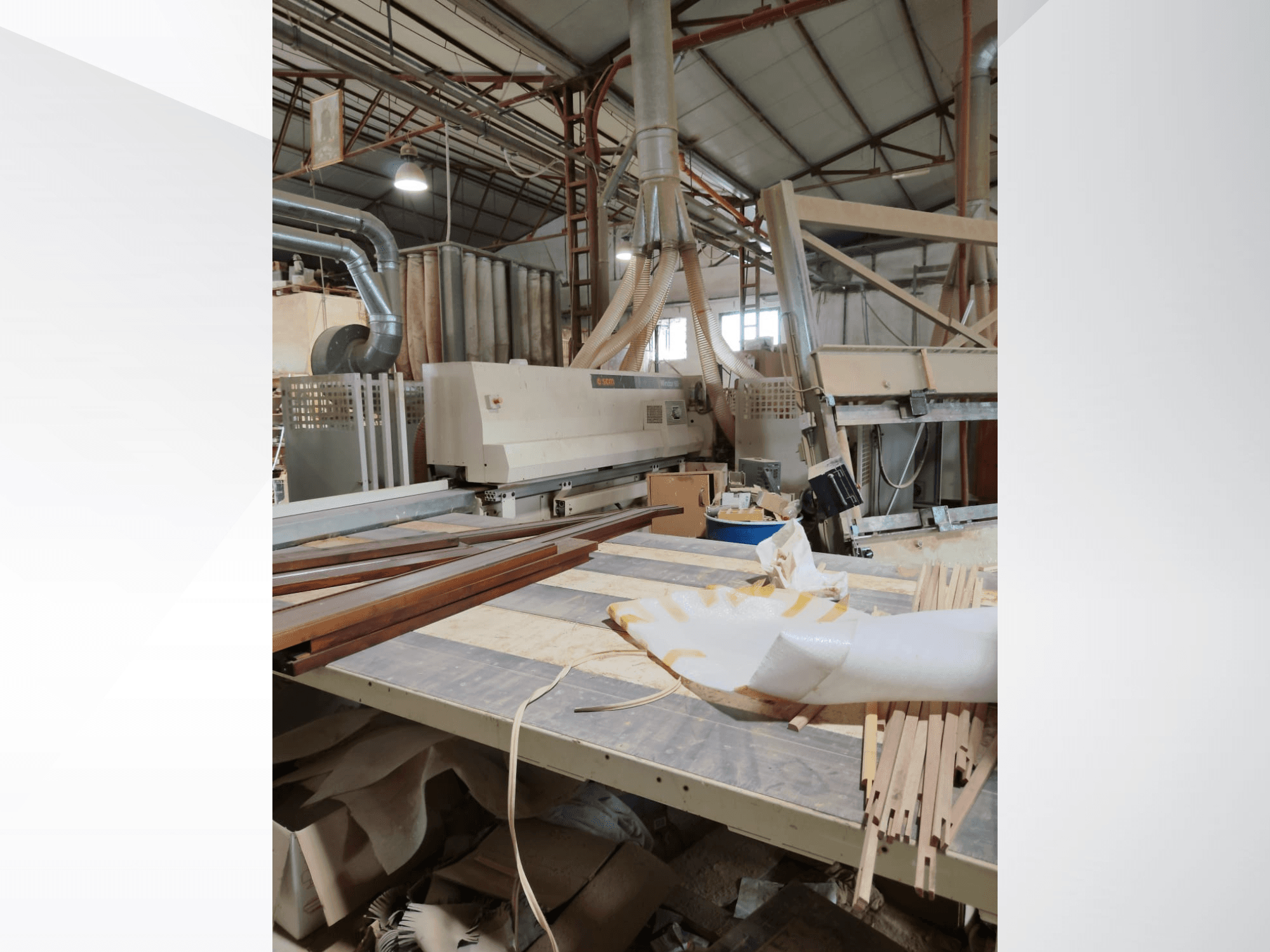 Centro di lavorazione del legno a controllo numerico SCM Windor60 in un'officina, visto di lato con pannelli di legno e attrezzature per l'aspirazione delle polveri.